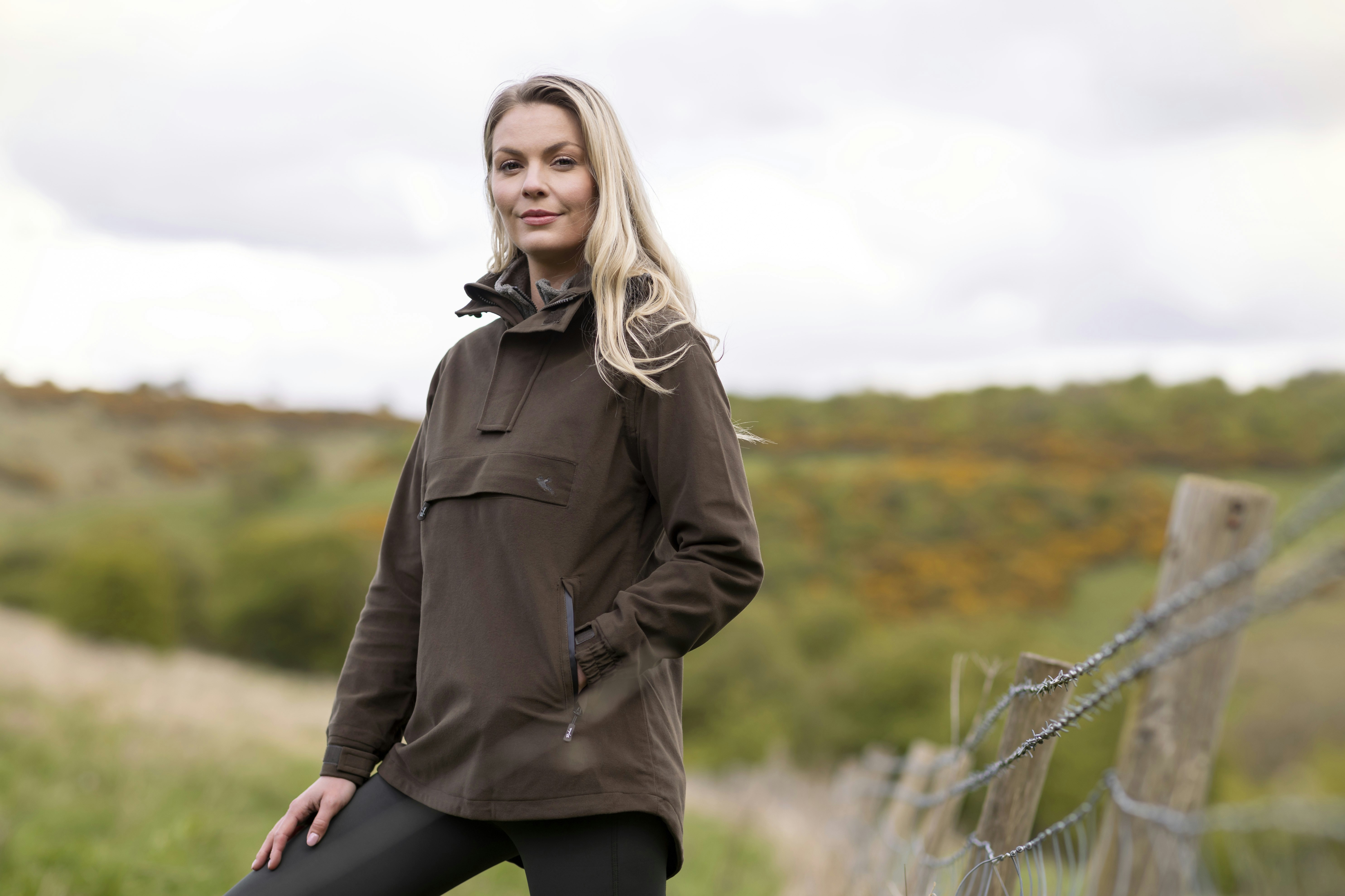 Eine Frau steht neben einem Stacheldrahtzaun