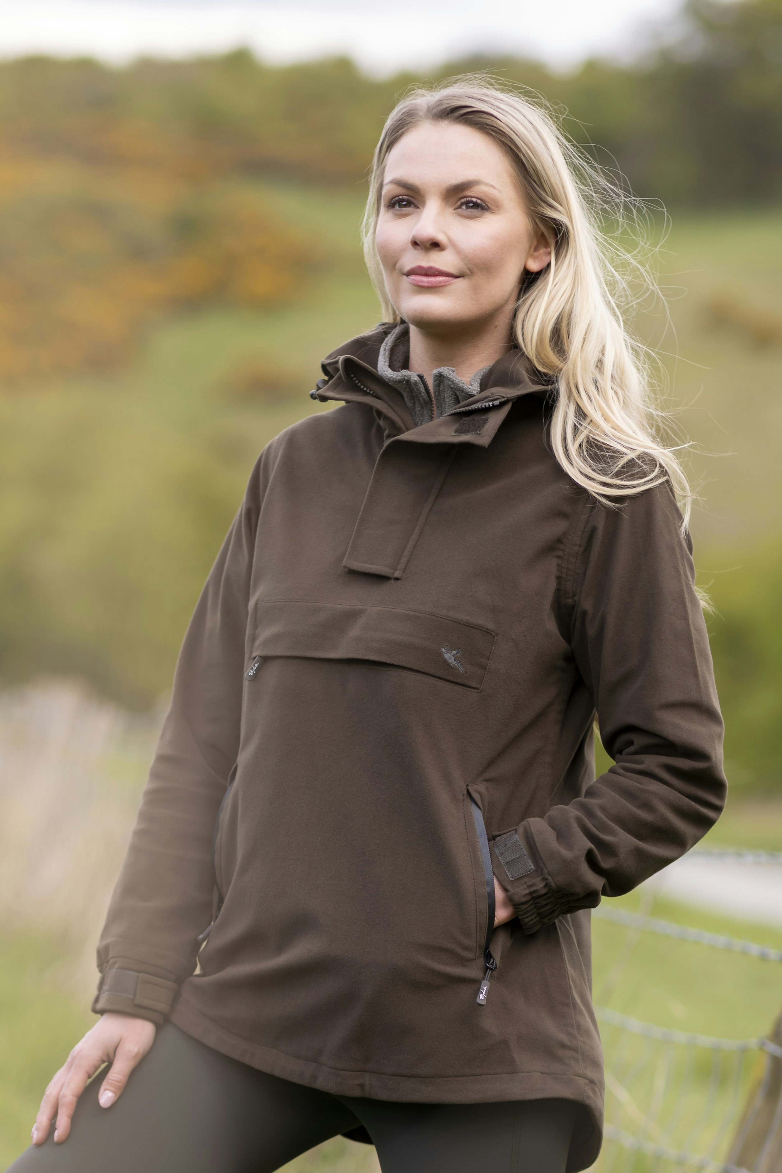 Eine Frau, die neben einem Zaun steht und die Hände in die Hüften stemmt