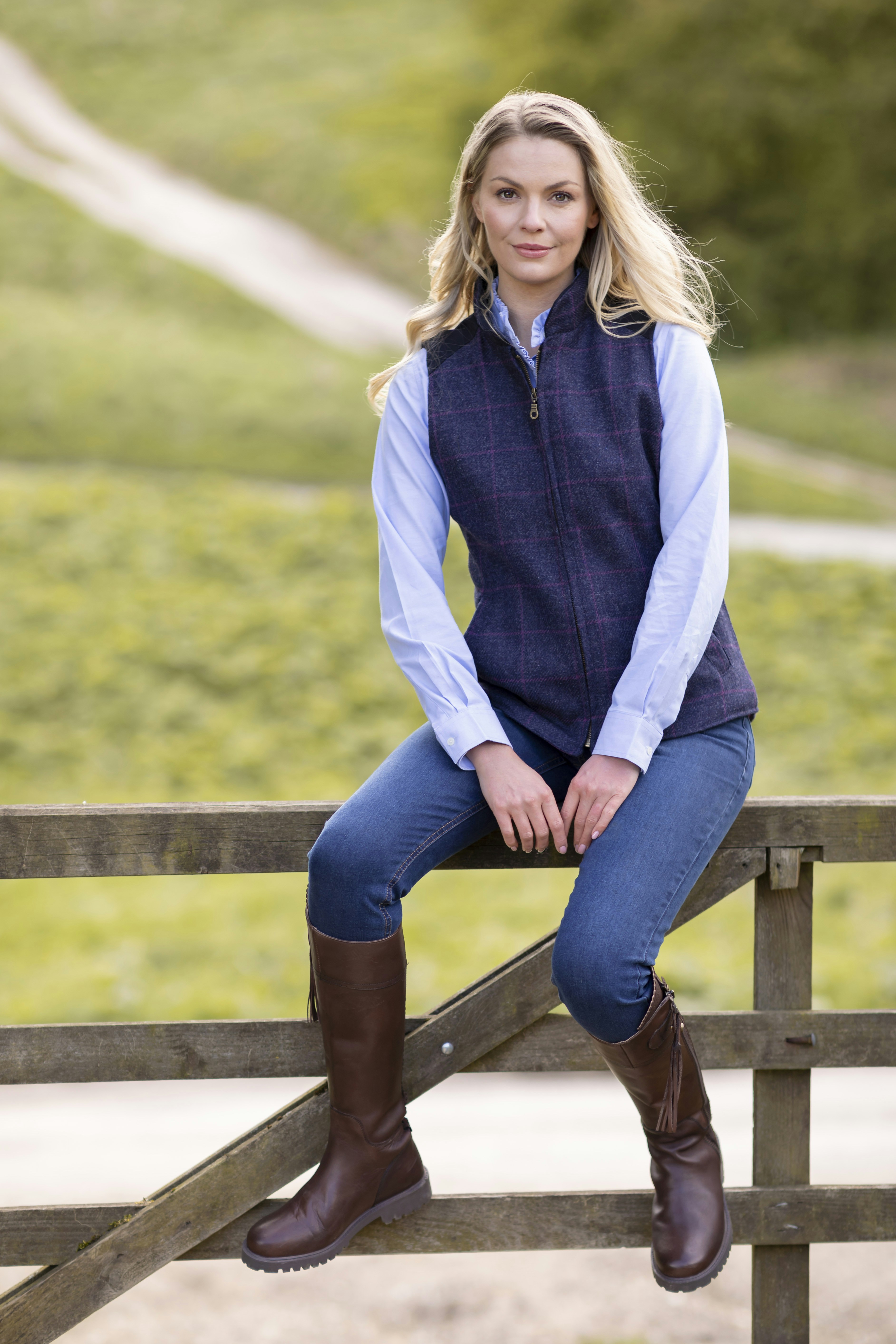 Une femme est assise sur une clôture et pose pour une photo