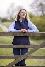 a woman leaning on a fence with her arms crossed