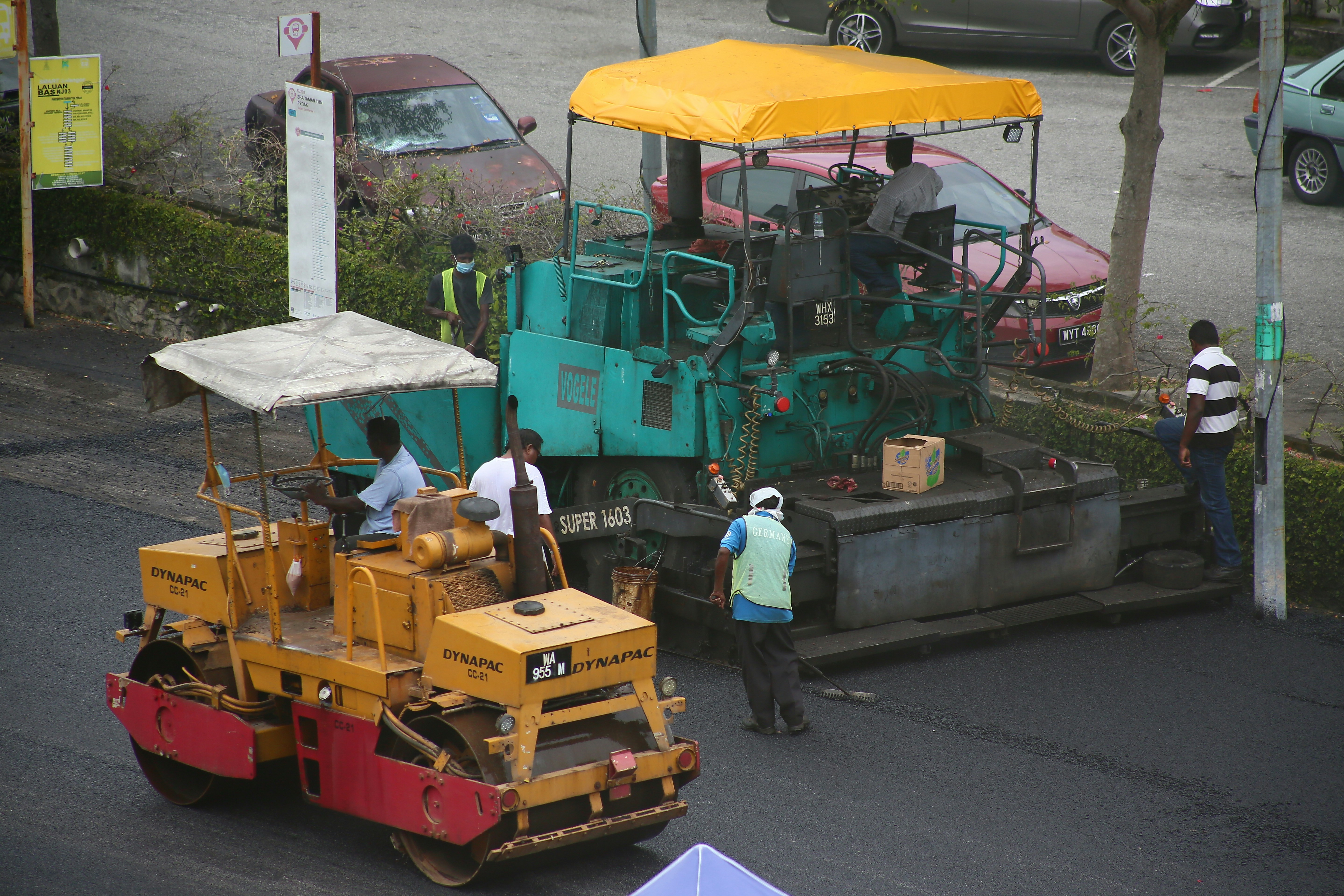 a man standing next to a road roller on the side of a road