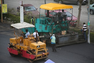 a man standing next to a road roller on the side of a road