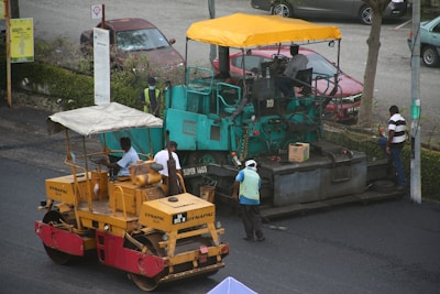 a man standing next to a road roller on the side of a road