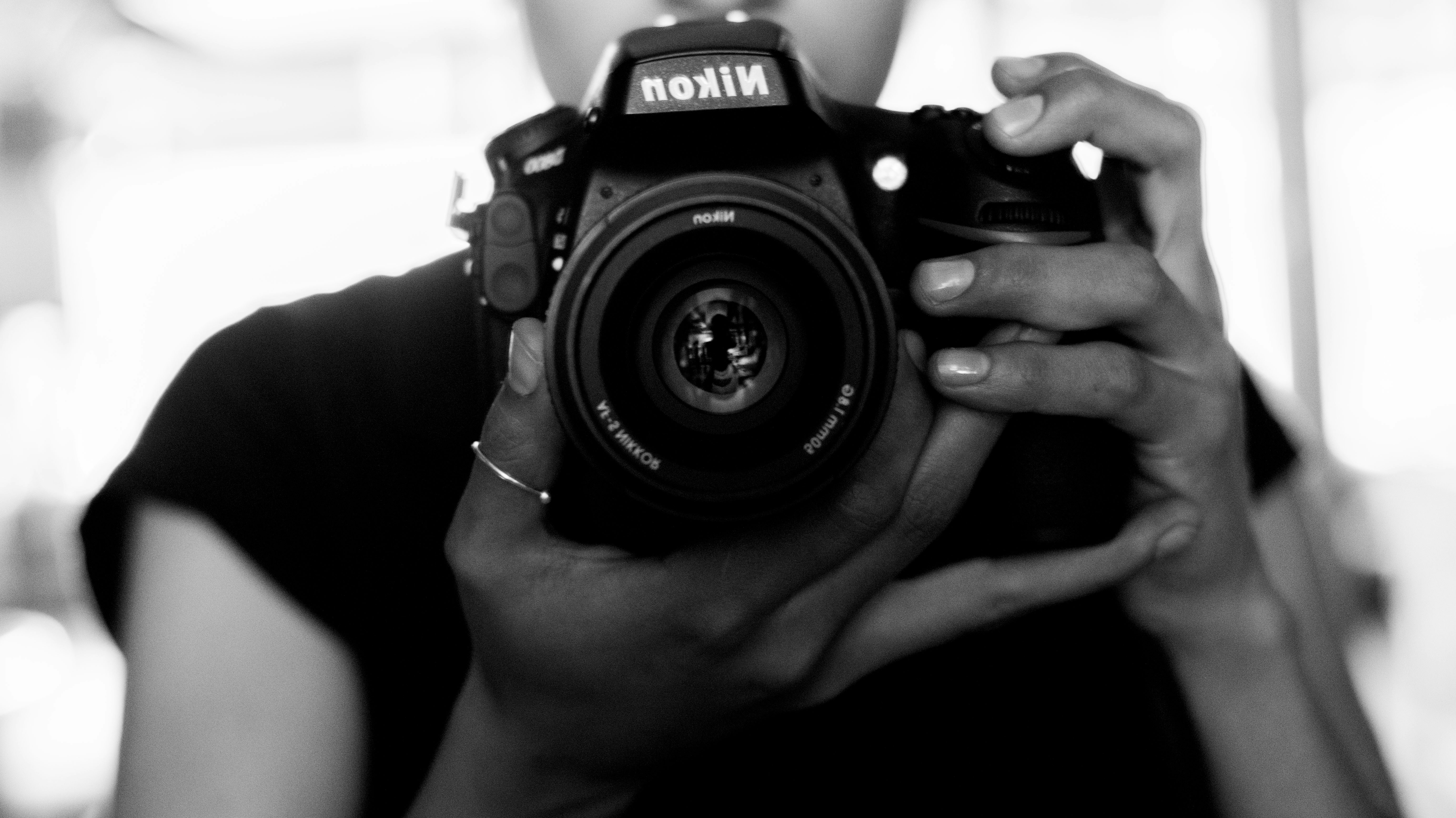 a black and white photo of a woman holding a camera