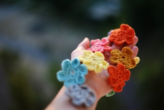 a hand holding a bunch of crocheted flowers