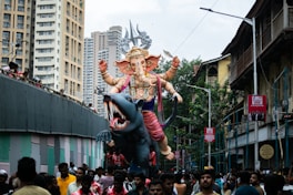 a group of people walking down a street next to a giant statue of an elephant