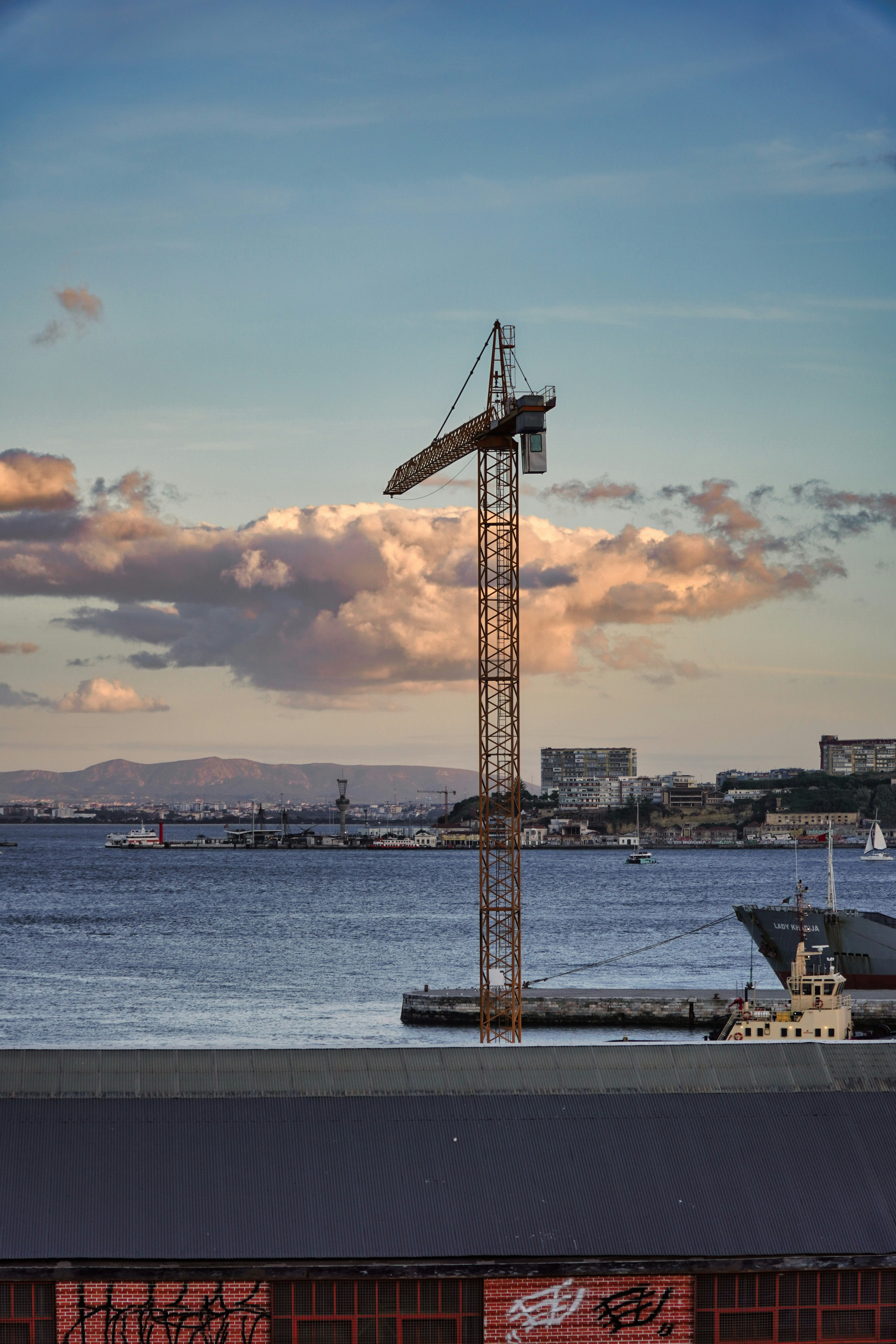 a crane on the side of a building next to a body of water