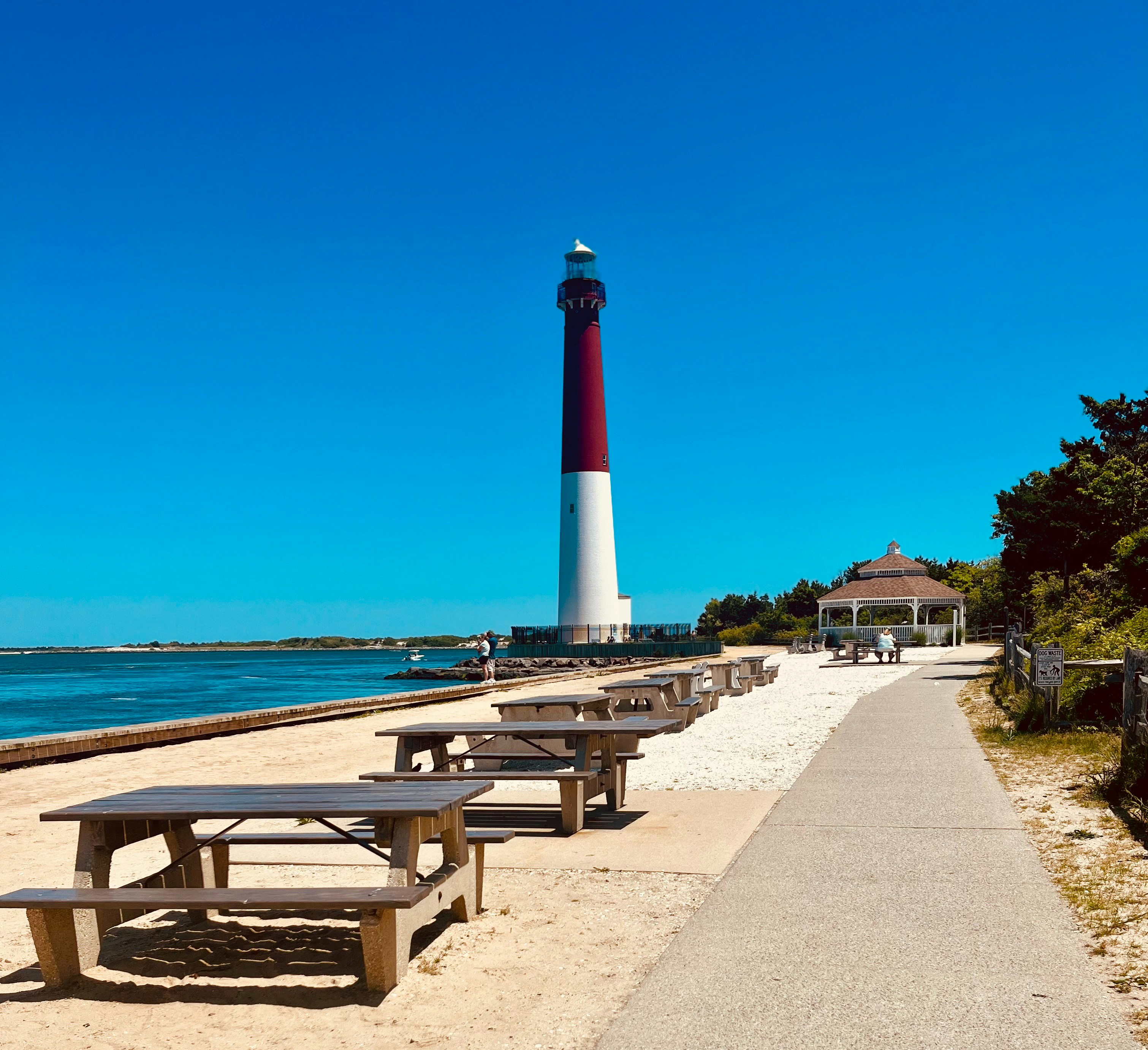 a beach with benches and a lighthouse in the background