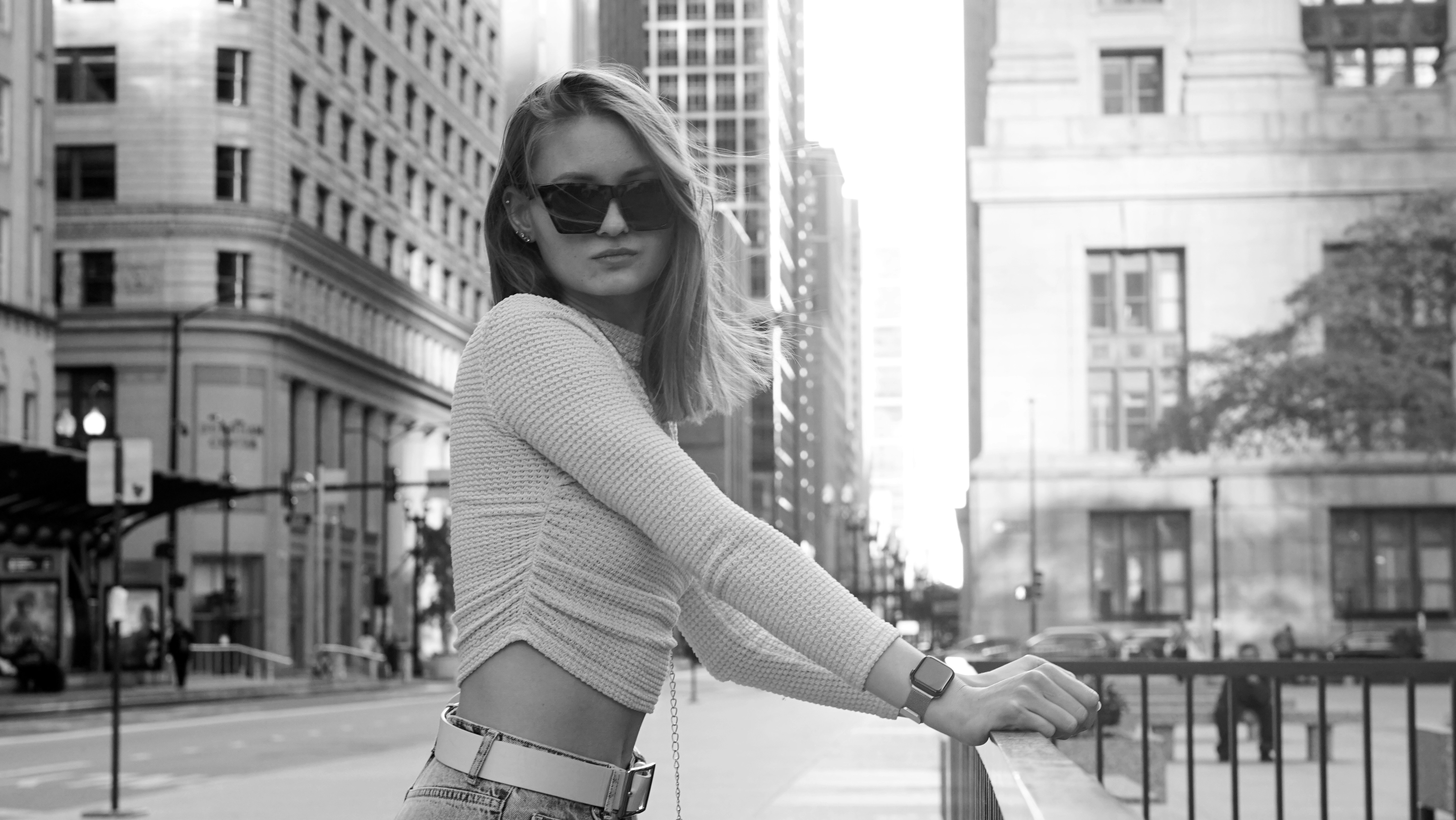 a woman in a short skirt and sunglasses leaning on a rail