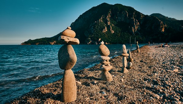 Stacked stones on the pebbles at Çıralı, the headland behind