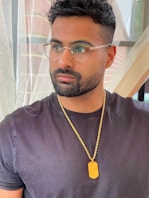 a man wearing glasses and a necklace with a tag on it