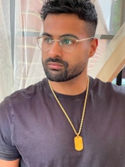 a man wearing glasses and a necklace with a tag on it