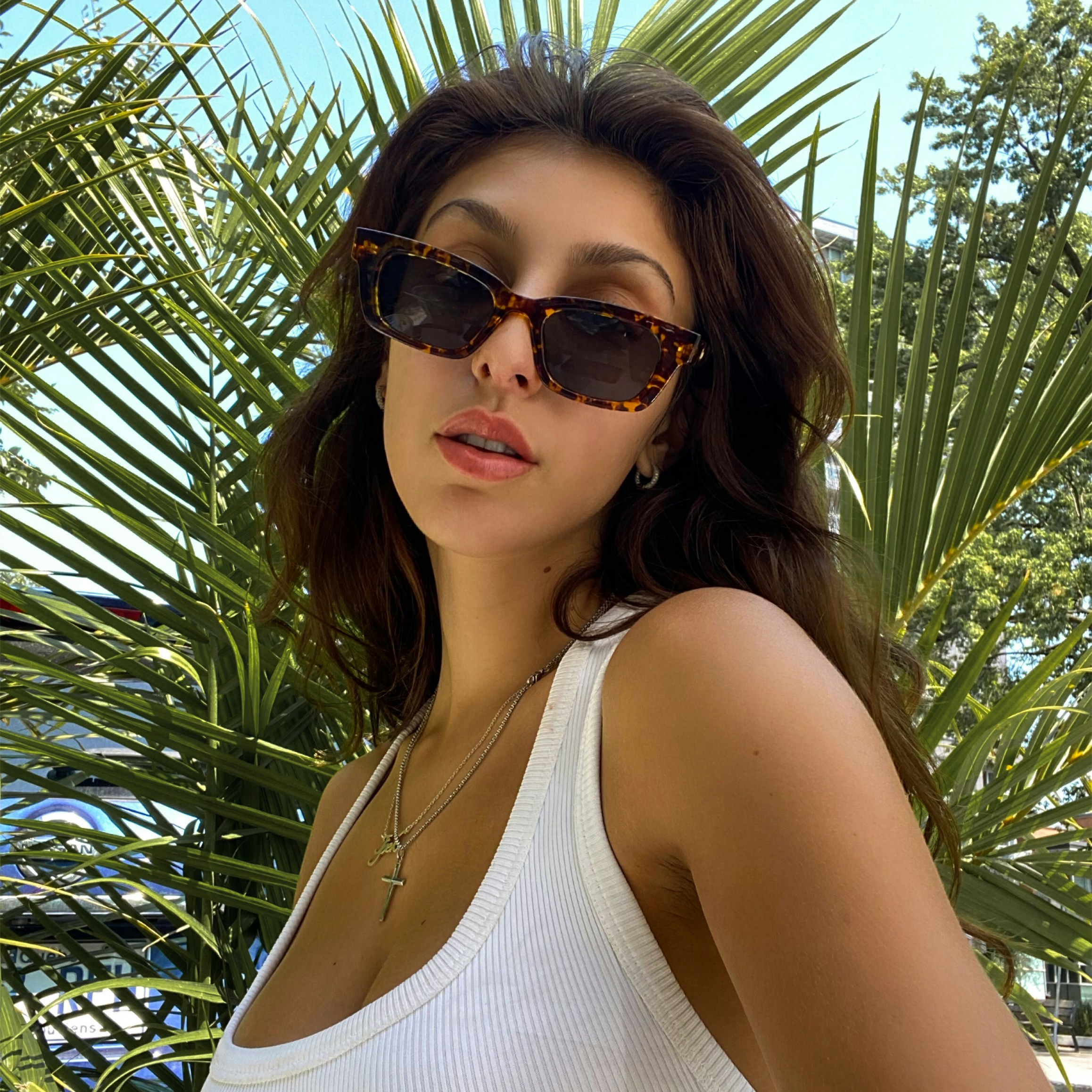 a woman in a white tank top and sunglasses
