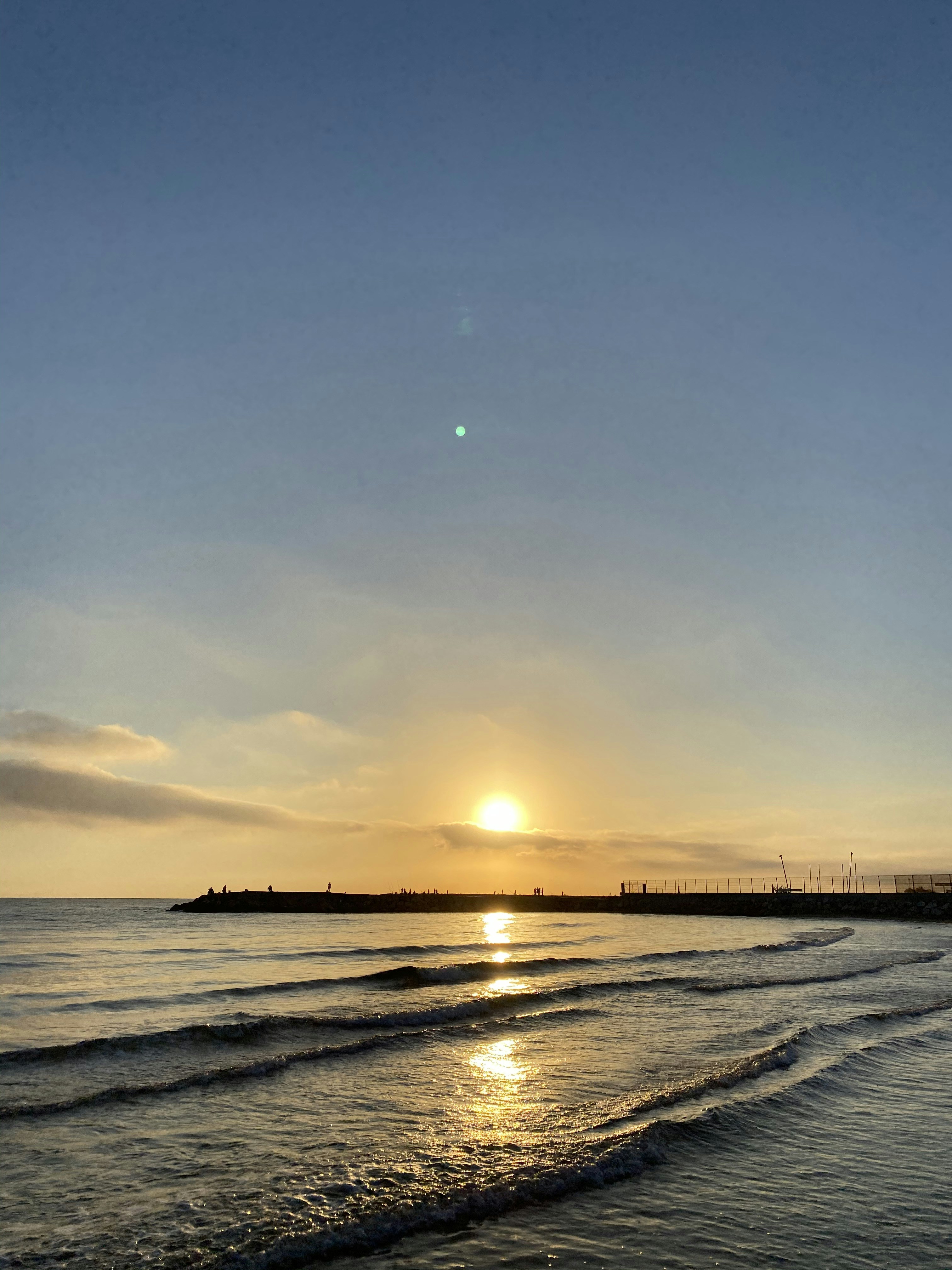 the sun is setting over the water at the beach
