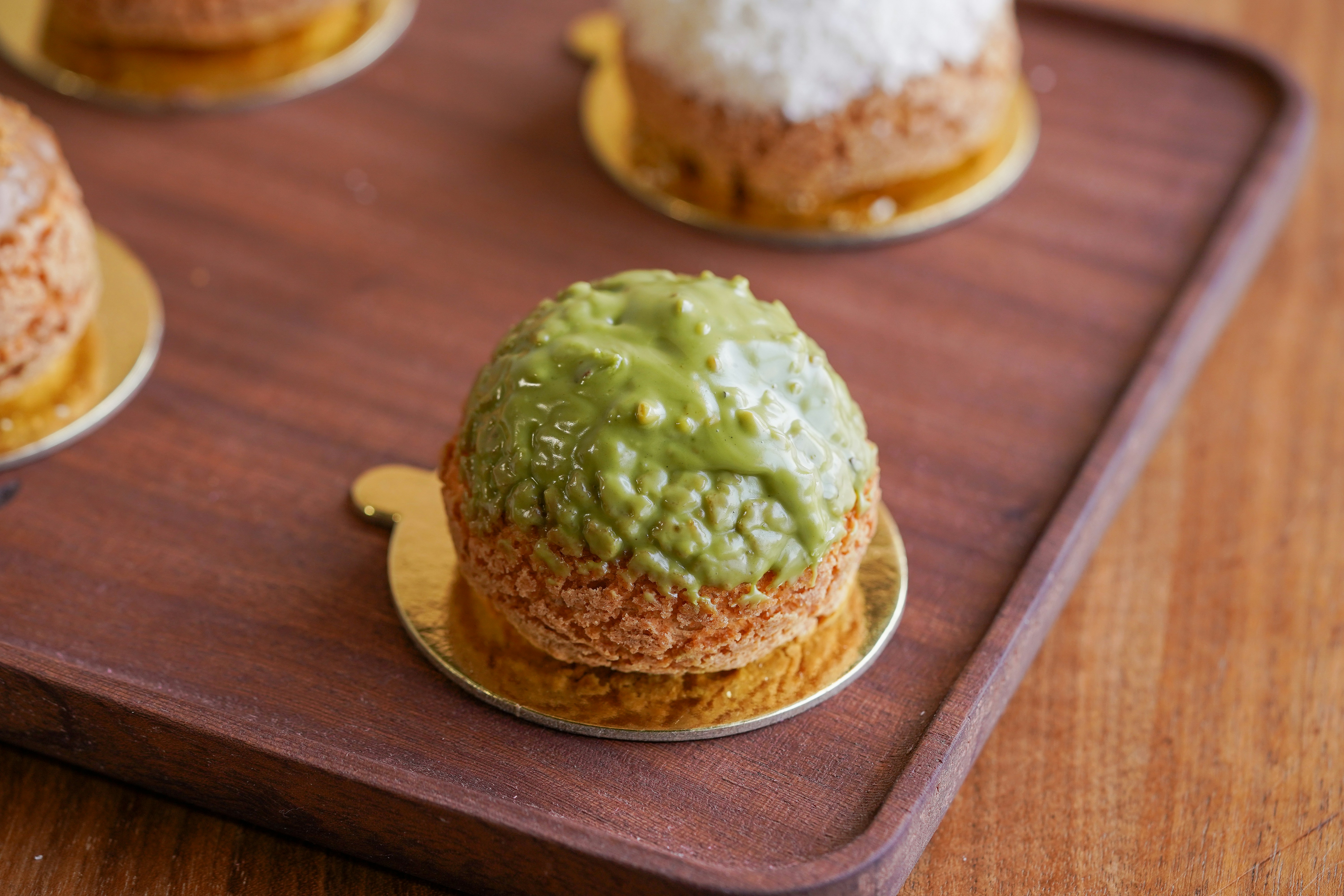 Matcha cream puffs on a wooden tray