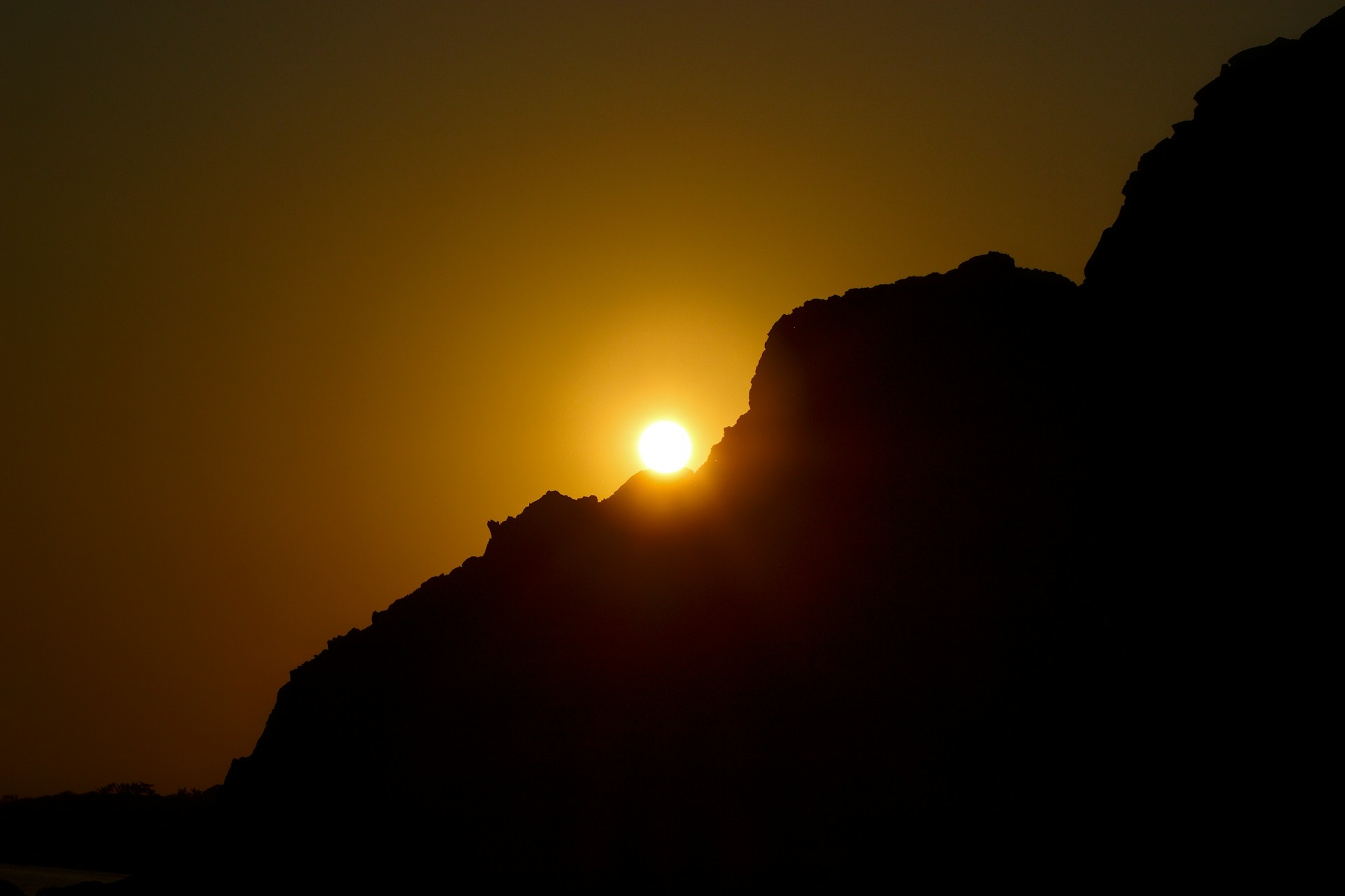 the sun is setting behind a mountain side