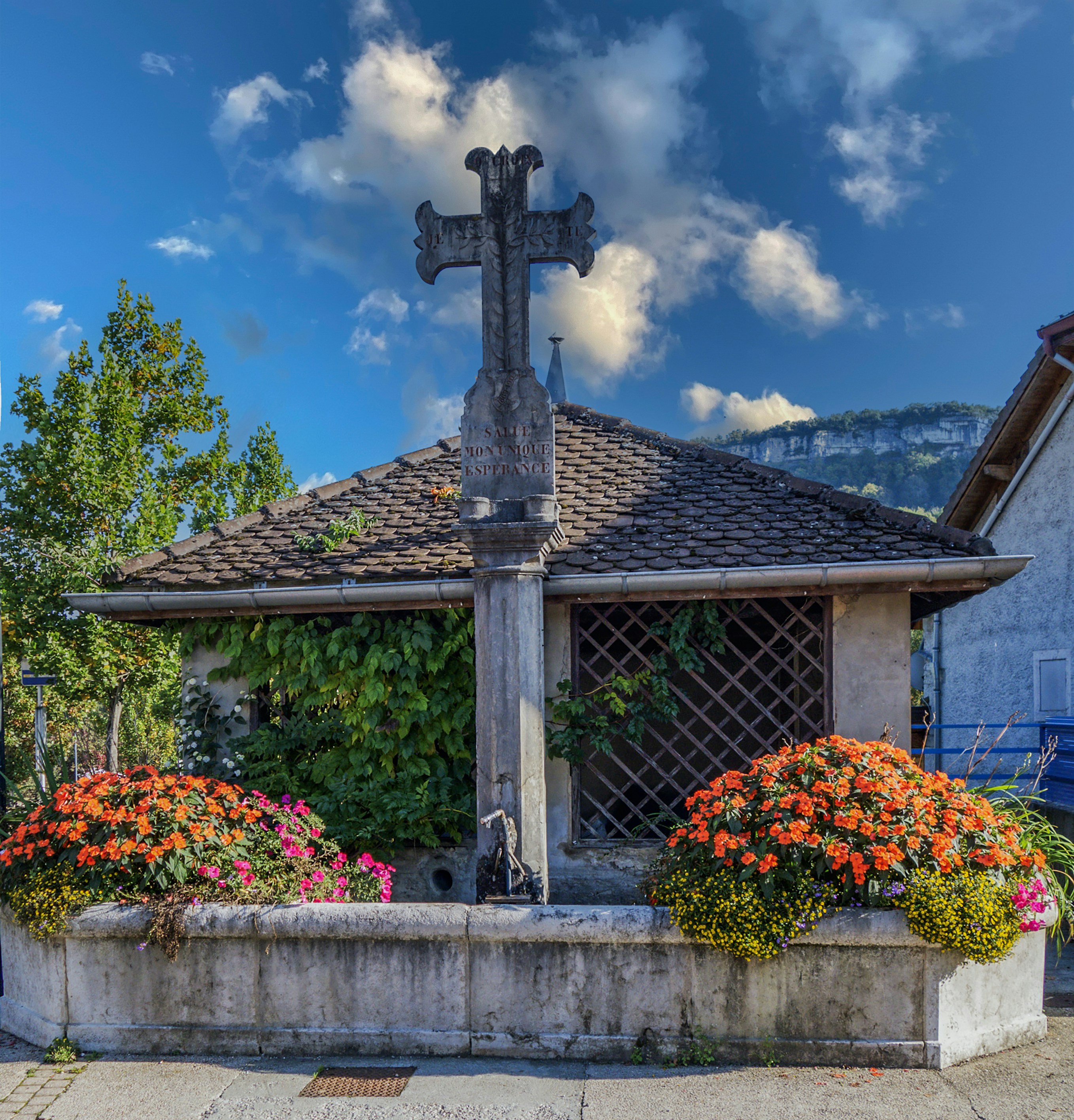 a cross on top of a building with flowers around it