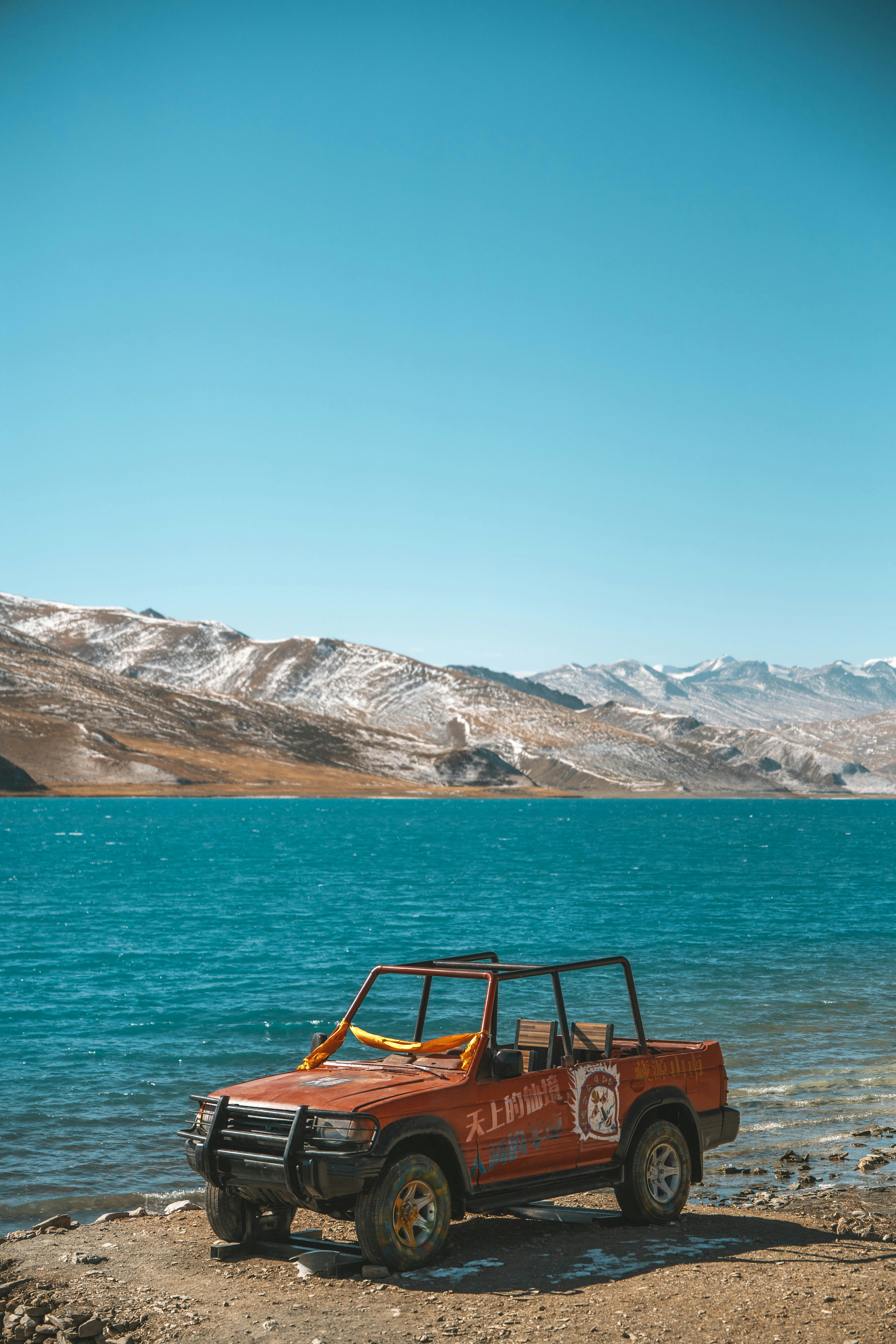 a jeep parked on the shore of a lake