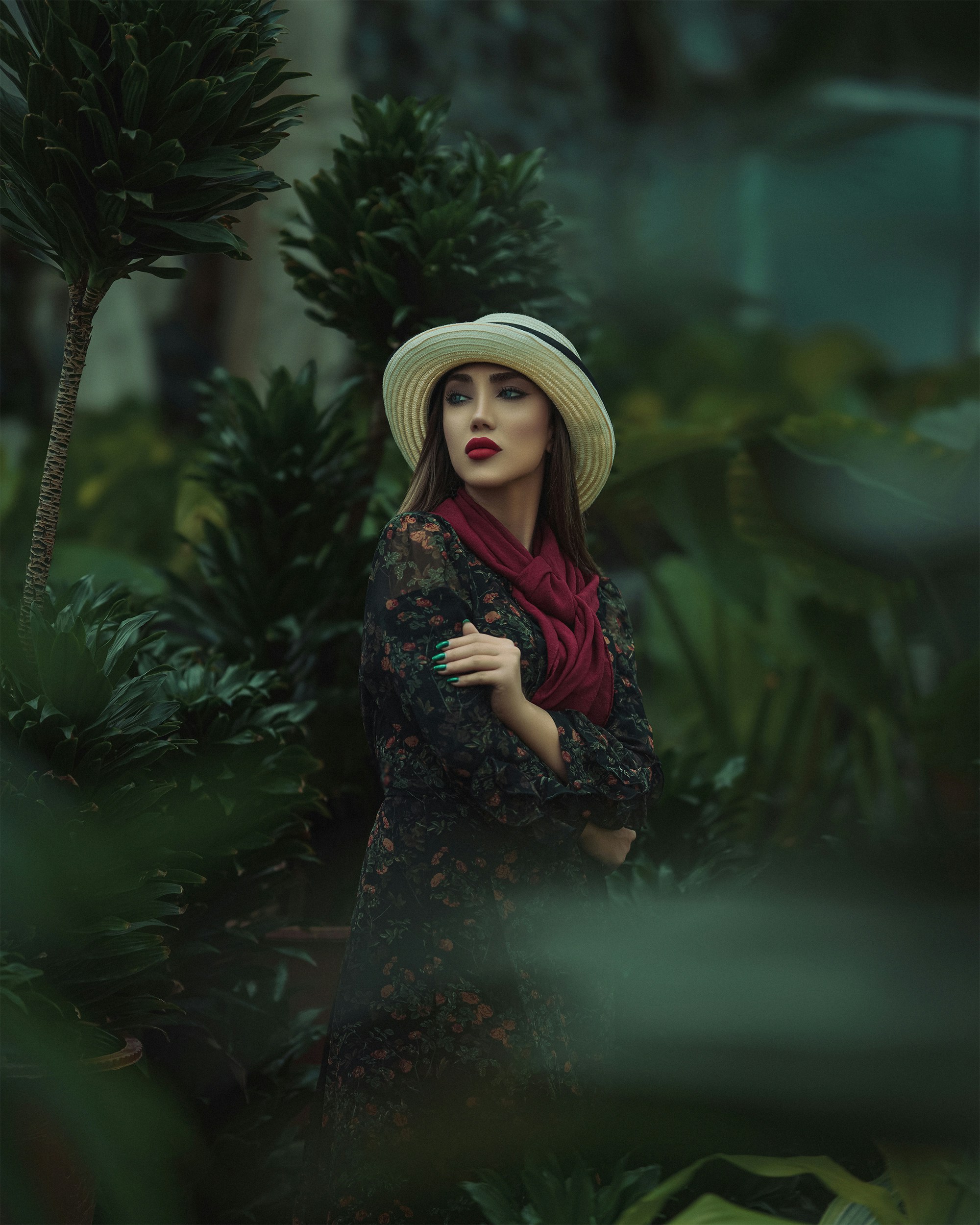 a woman wearing a hat and scarf standing in a forest