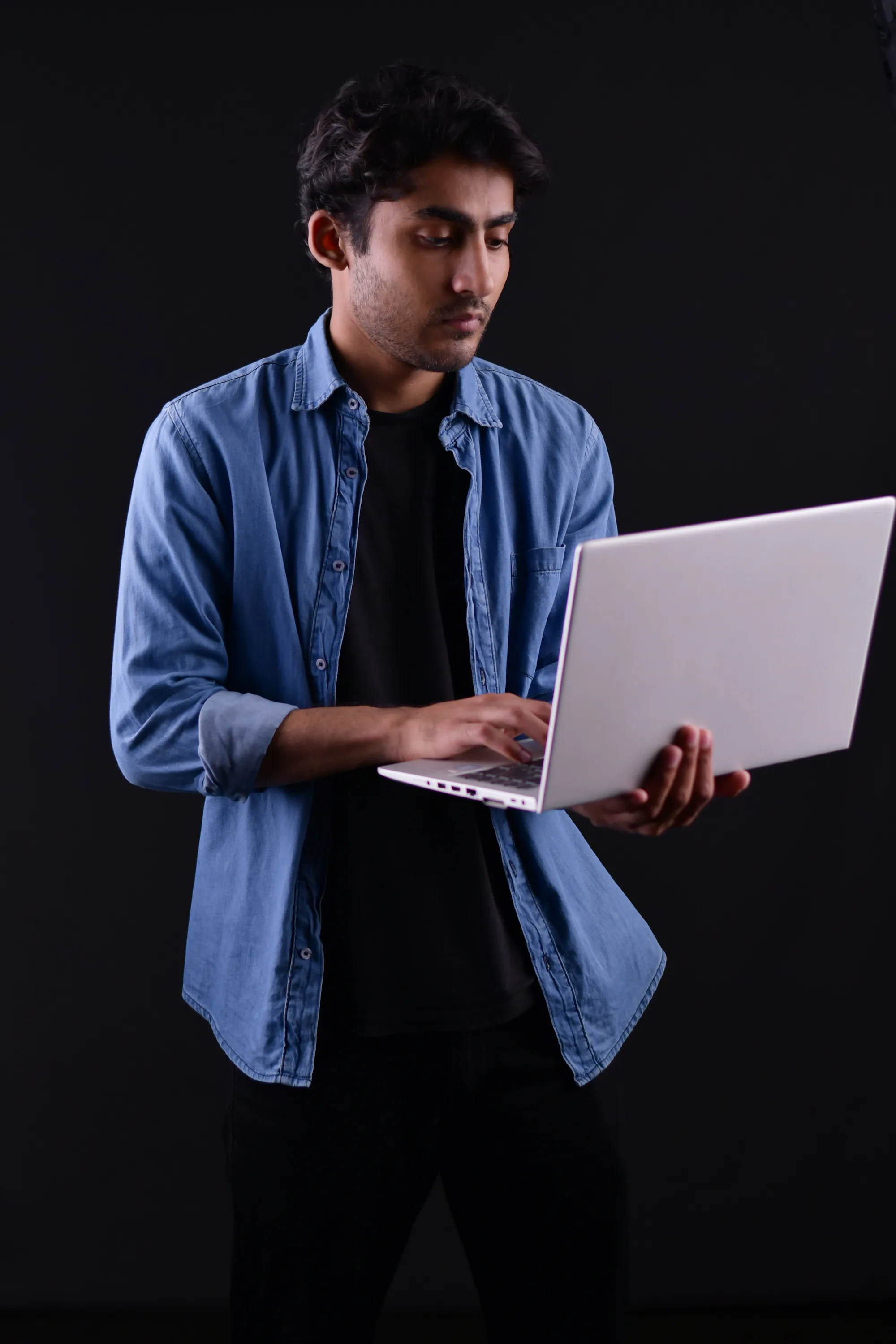 A man in a blue shirt working on a laptop in Sialkot, Pakistan