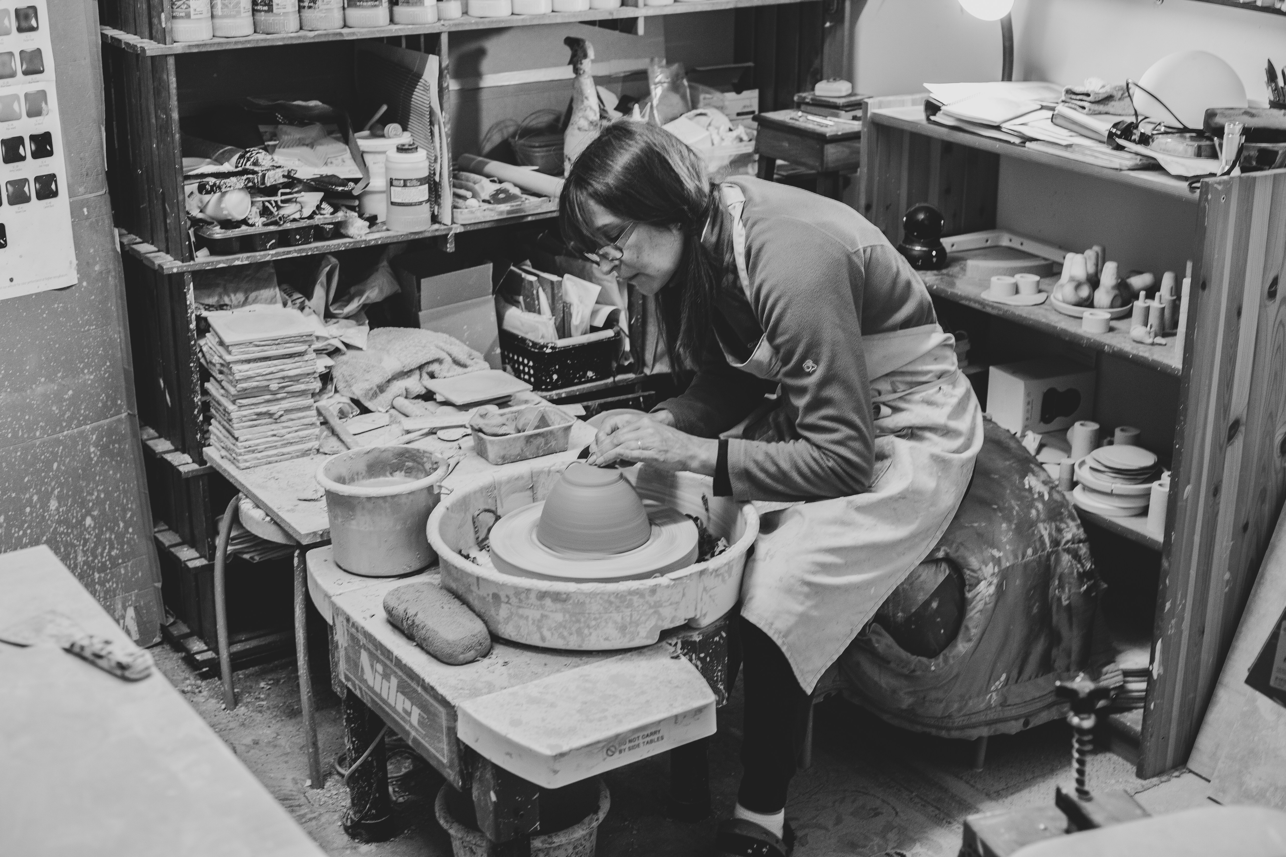 a woman working on a pottery wheel in a workshop
