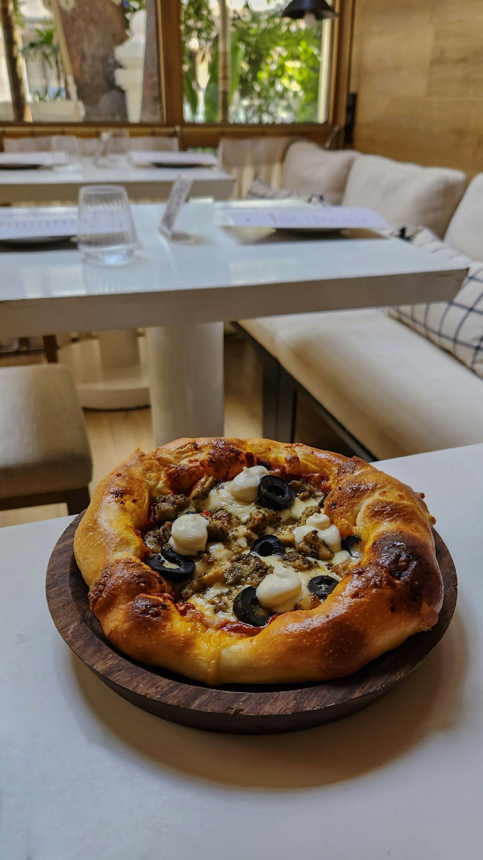 una pizza encima de un plato de madera sobre una mesa