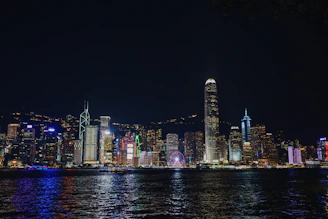 a city skyline at night with lights reflecting off the water