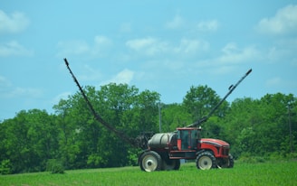 a red and black tractor in a green field