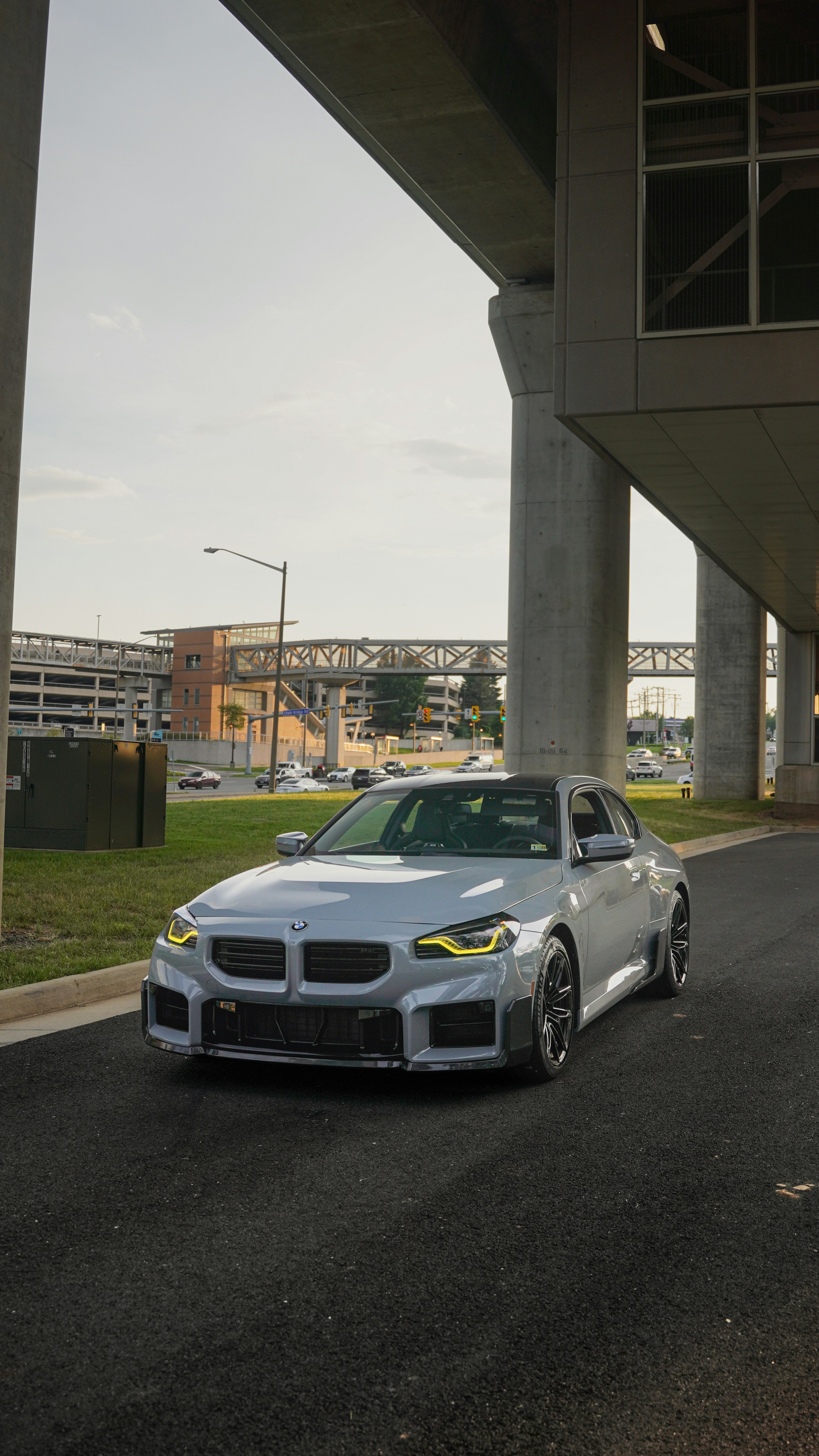 A white car is parked under a bridge