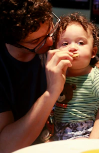 a man feeding a small child a piece of food