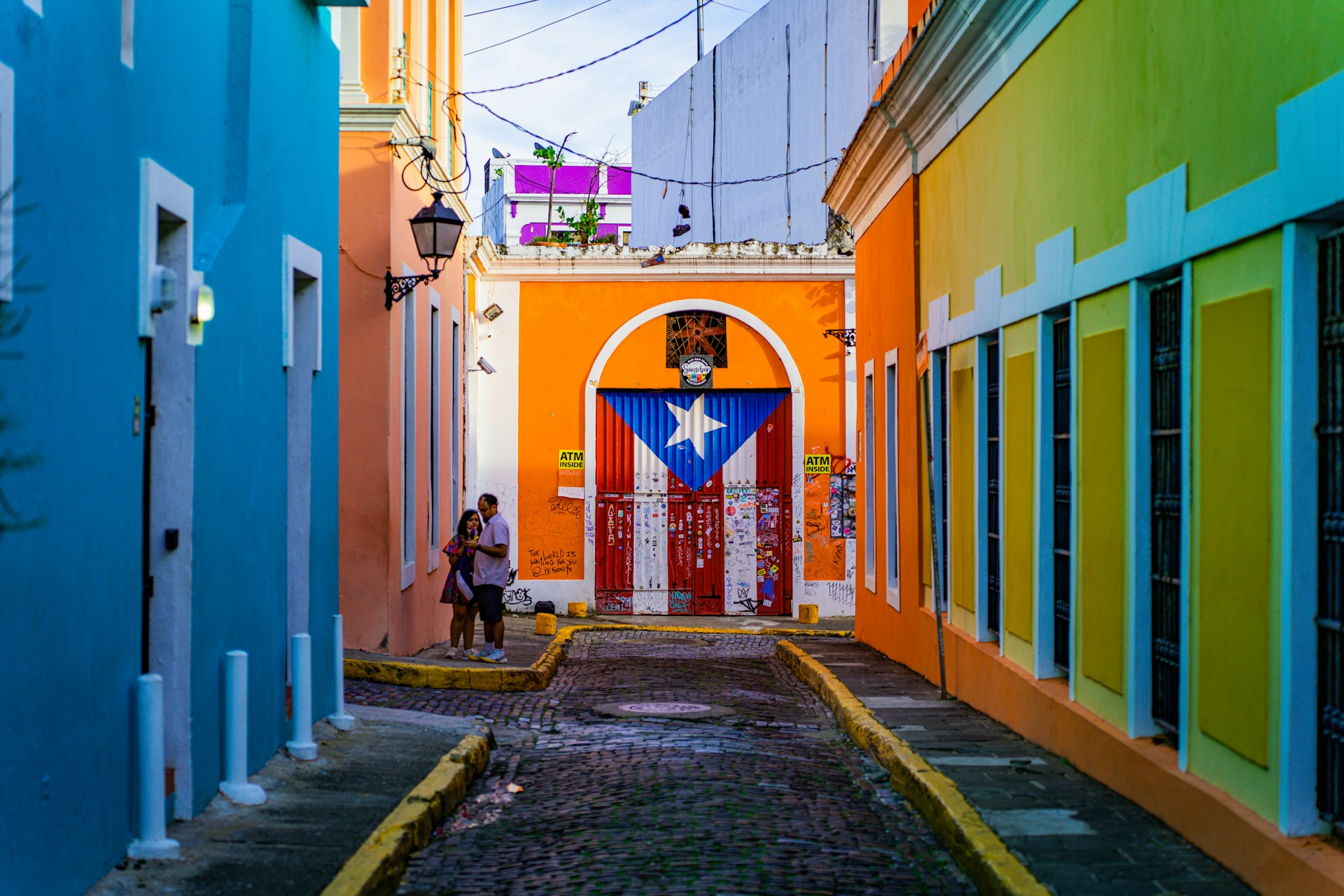 a narrow alley way with a colorful building and a flag on the door