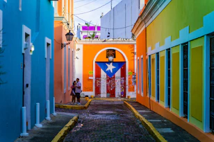 a narrow alley way with a colorful building and a flag on the door