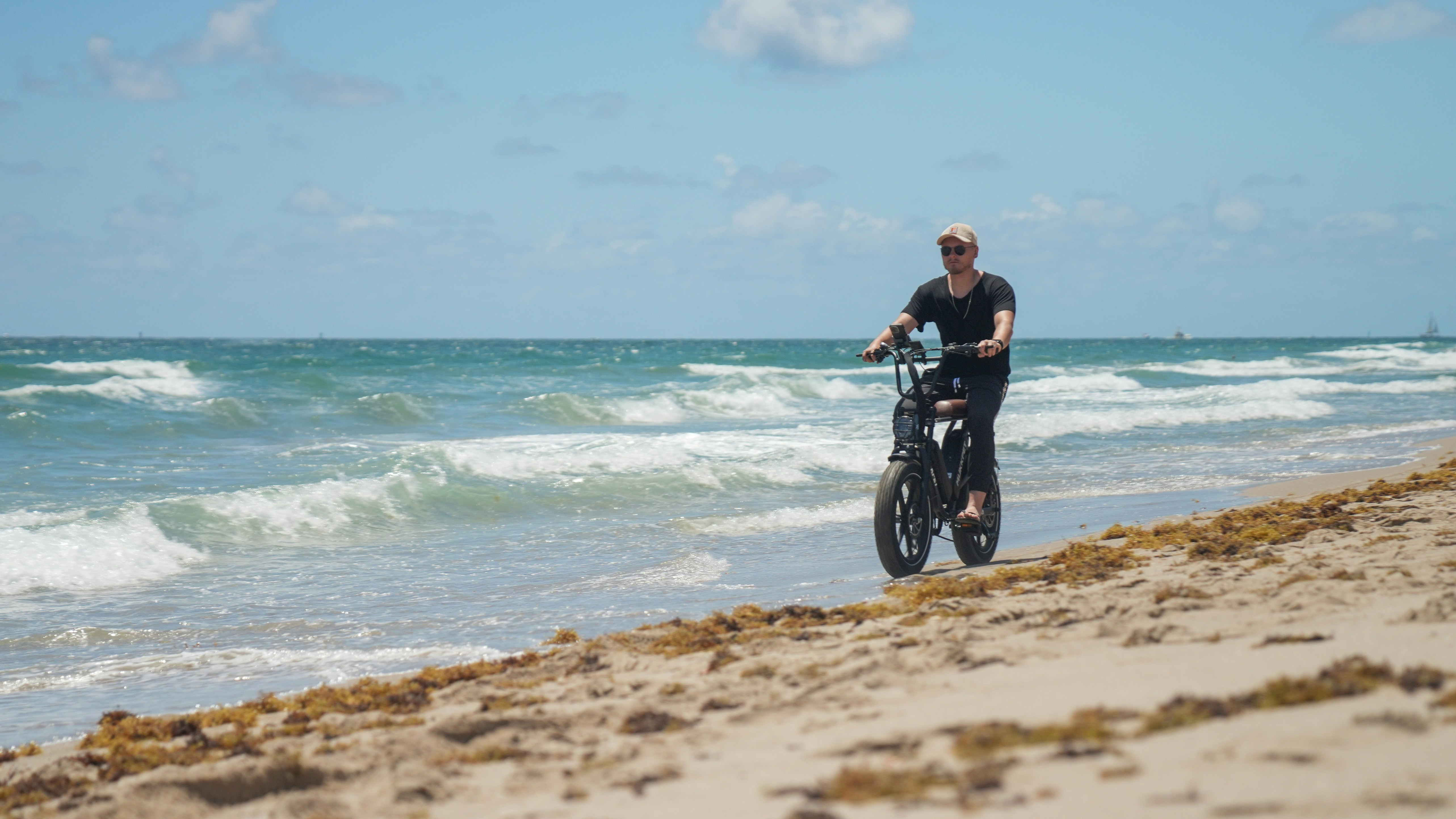 a man riding a bike on top of a sandy beach