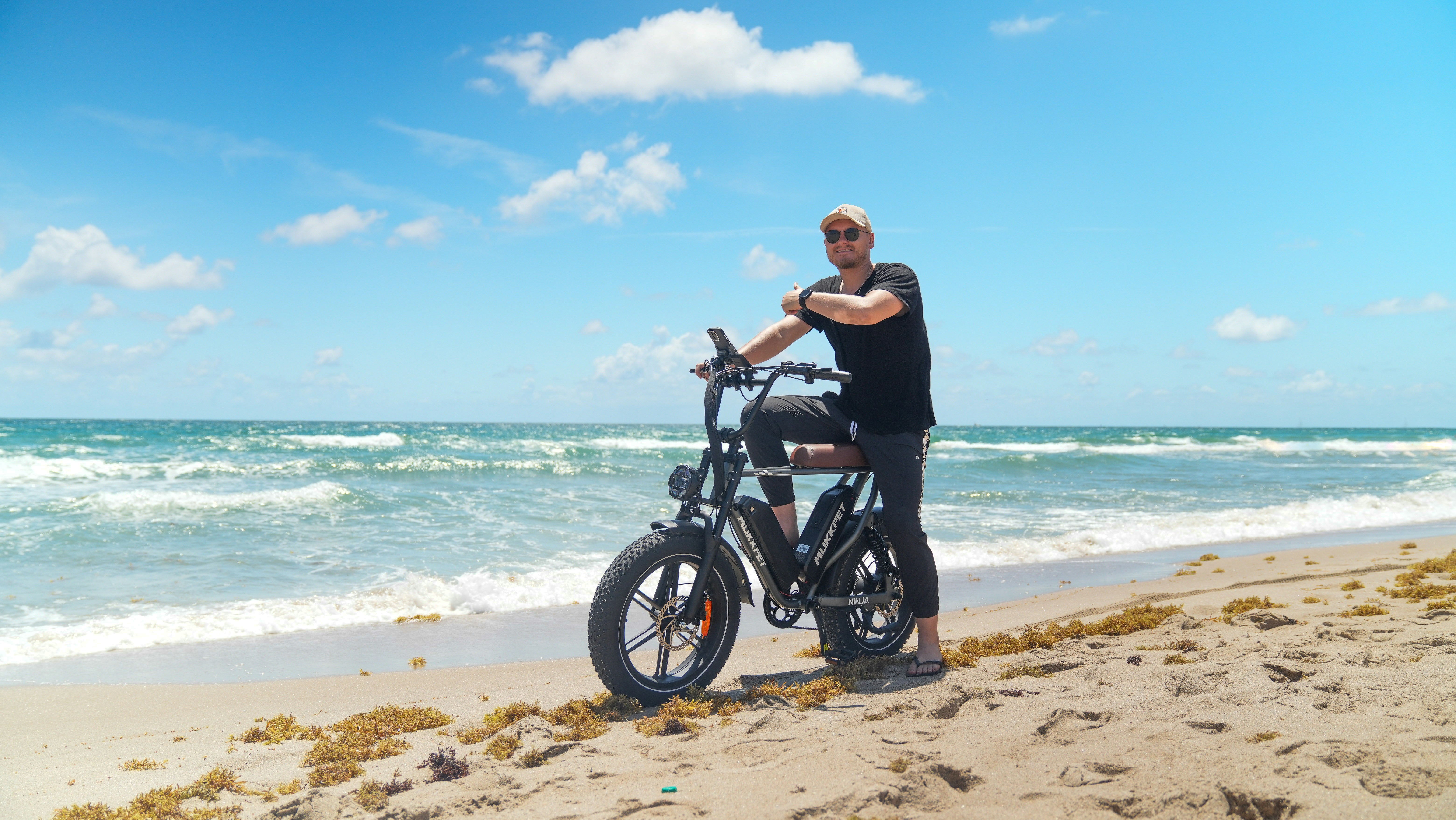 a man standing next to a bike on a beach