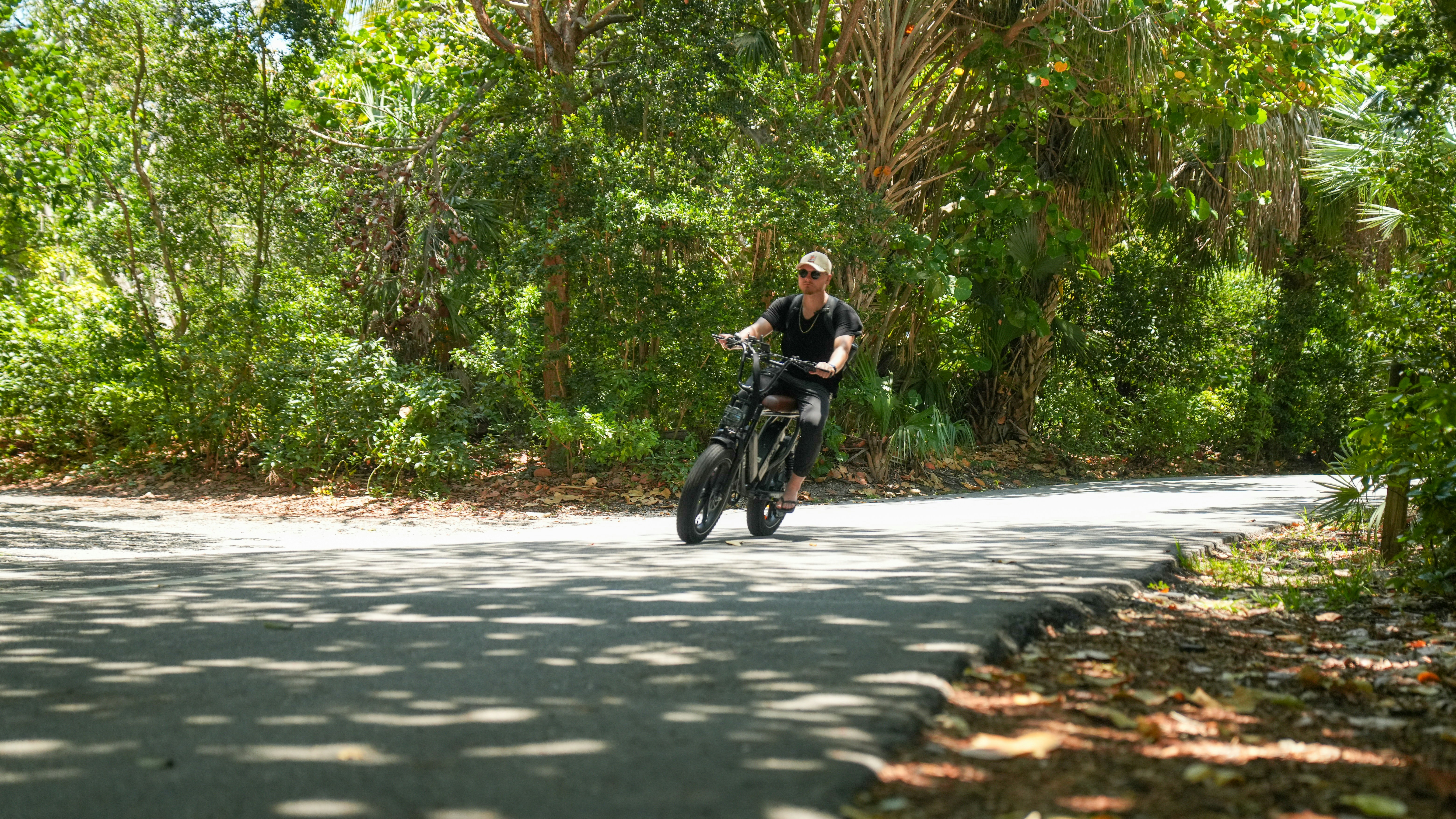 a man riding a motorcycle down a tree lined road