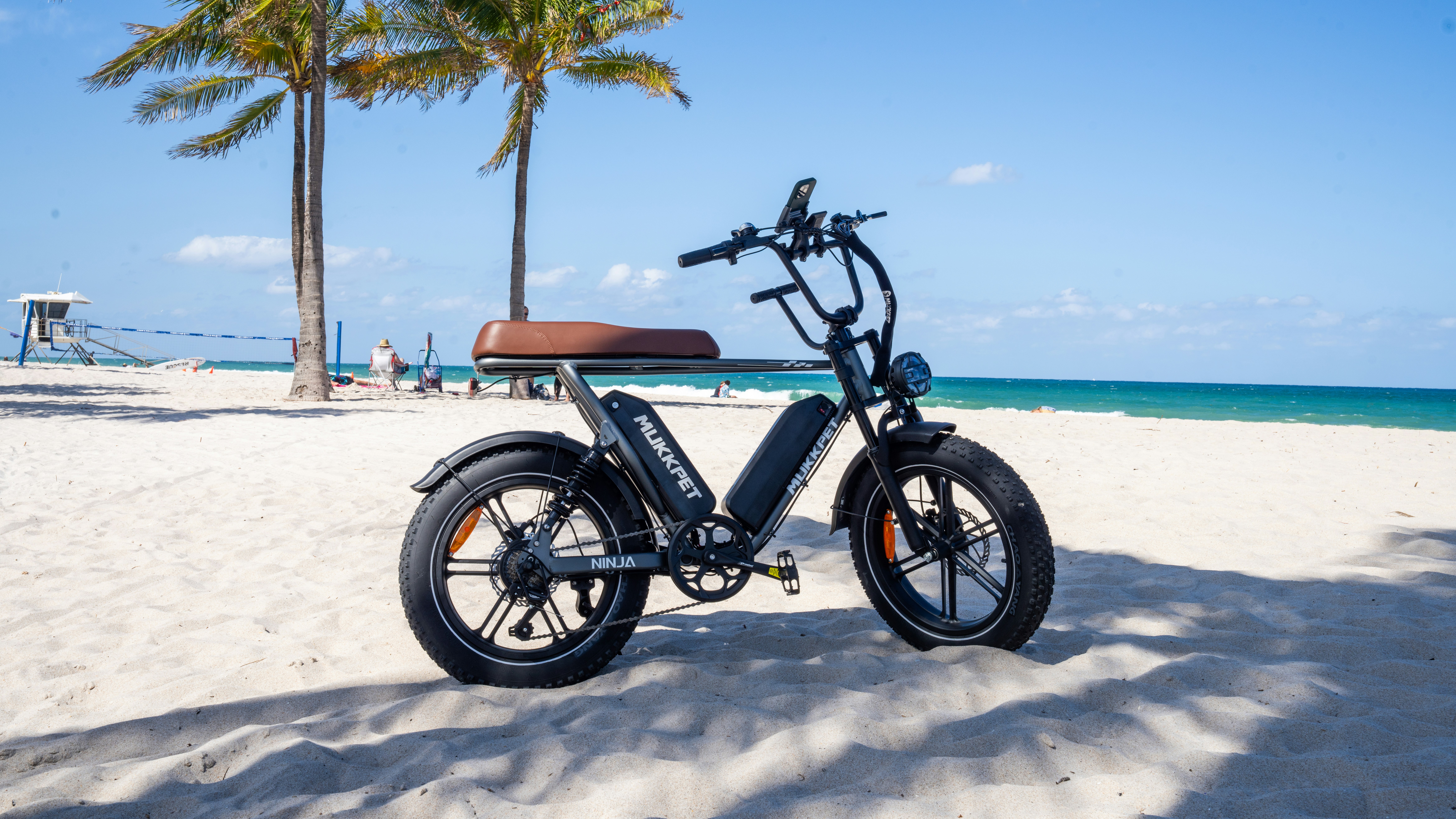 a scooter parked on a beach next to a palm tree