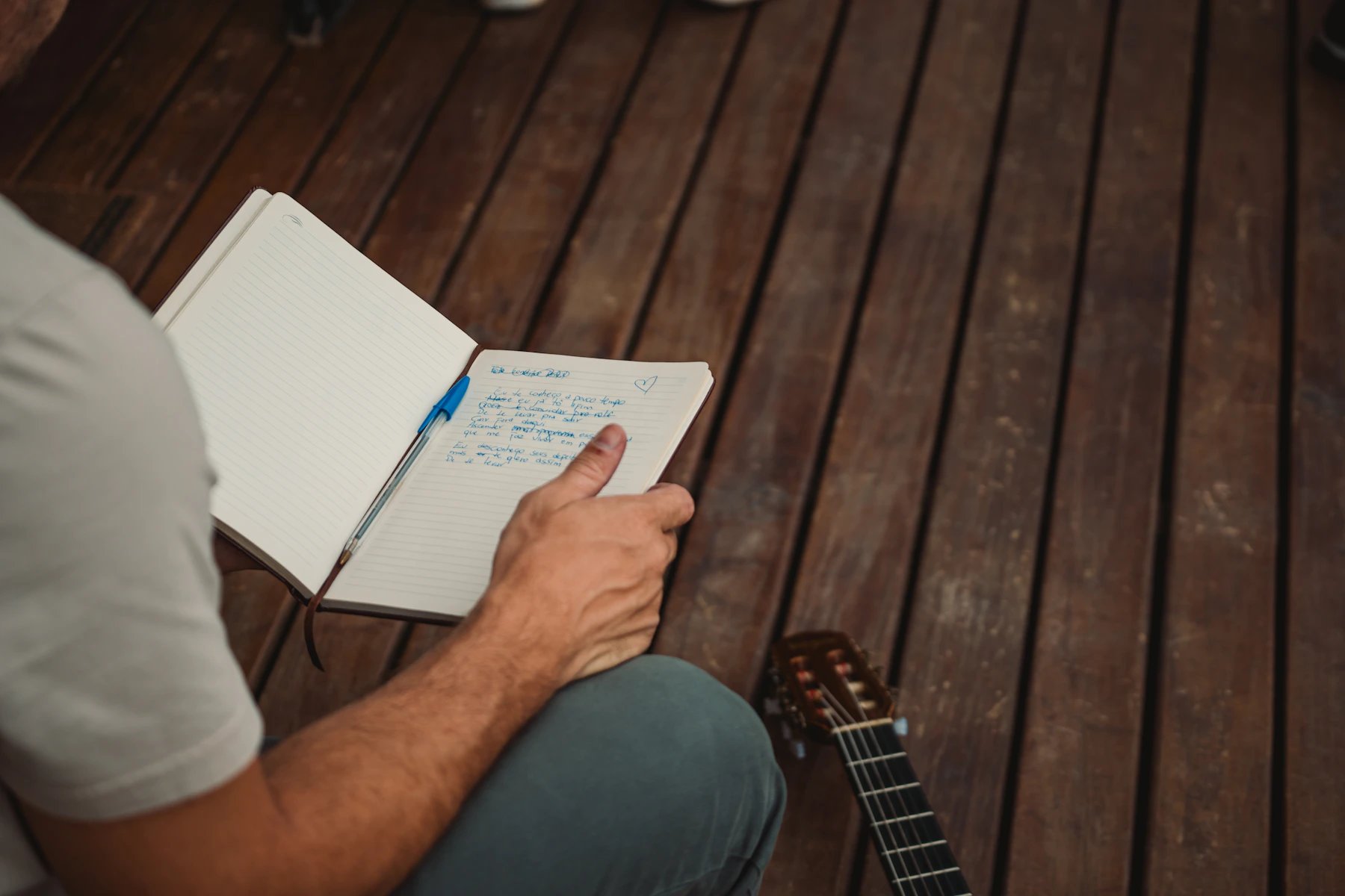 Persona con guitarra y libreta durante una sesión de escritura