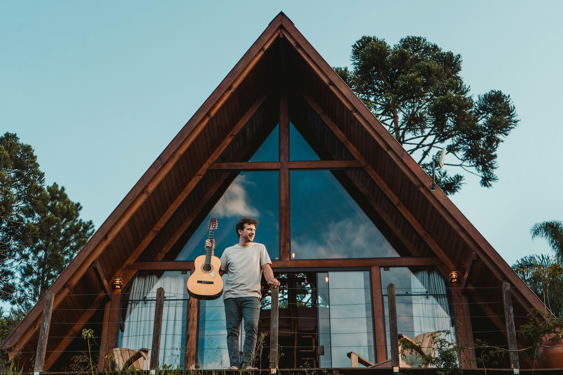a man holding a guitar standing in front of a house