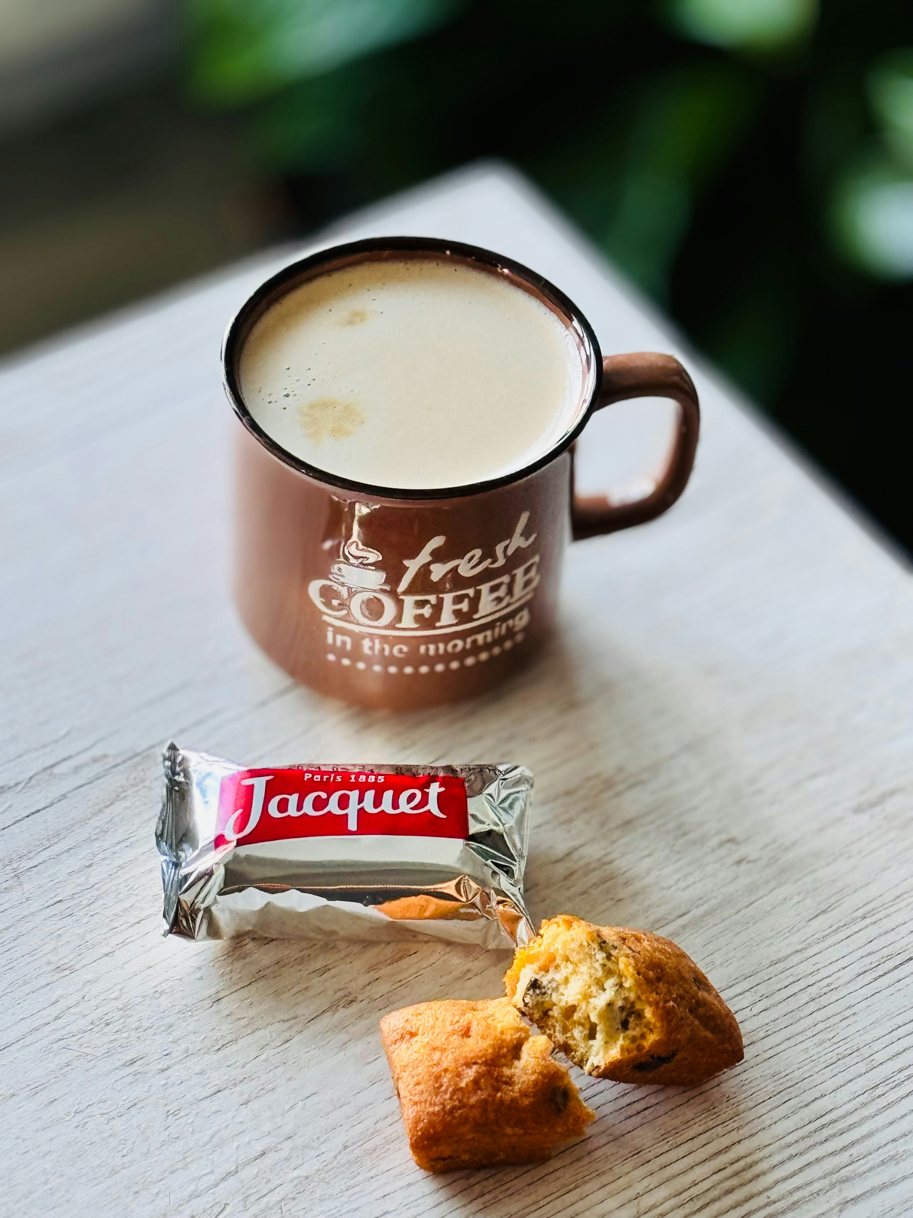 a cup of coffee and a biscuit on a table