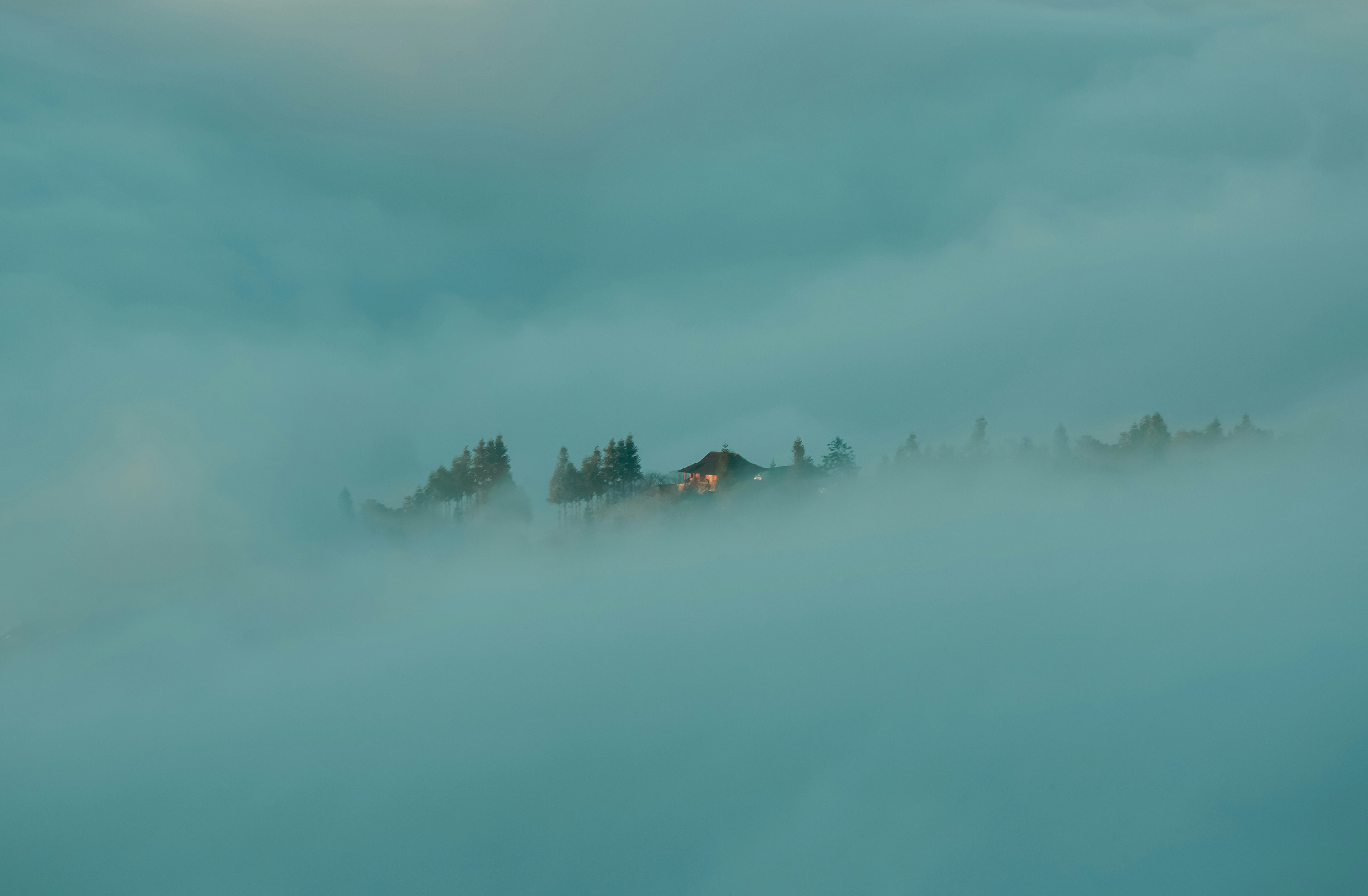 a foggy landscape with a house in the distance