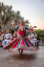 a woman in a colorful dress dancing in front of a group of people