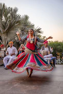 a woman in a colorful dress dancing in front of a group of people