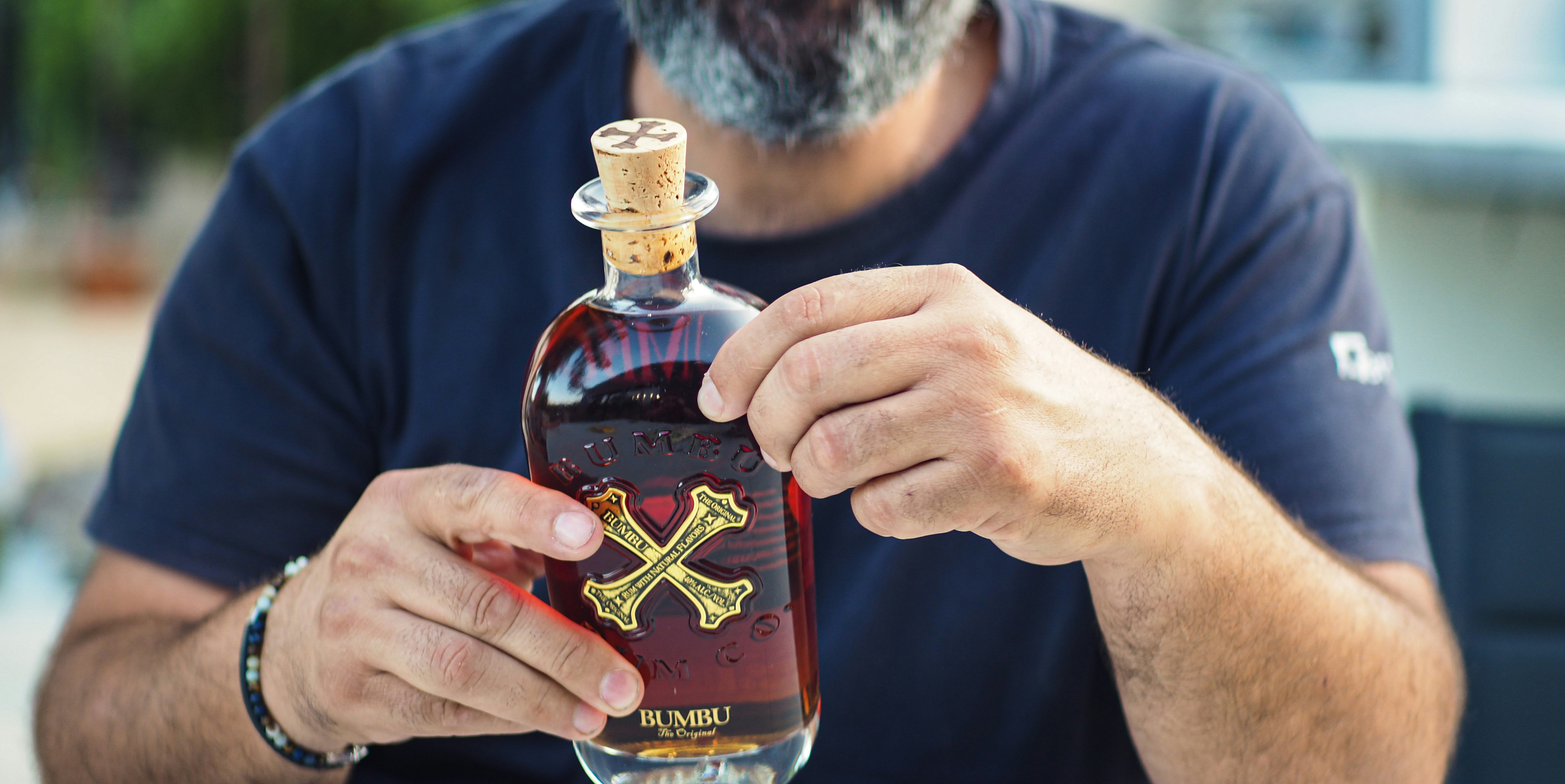 a man holding a bottle of liquor with a cross on it