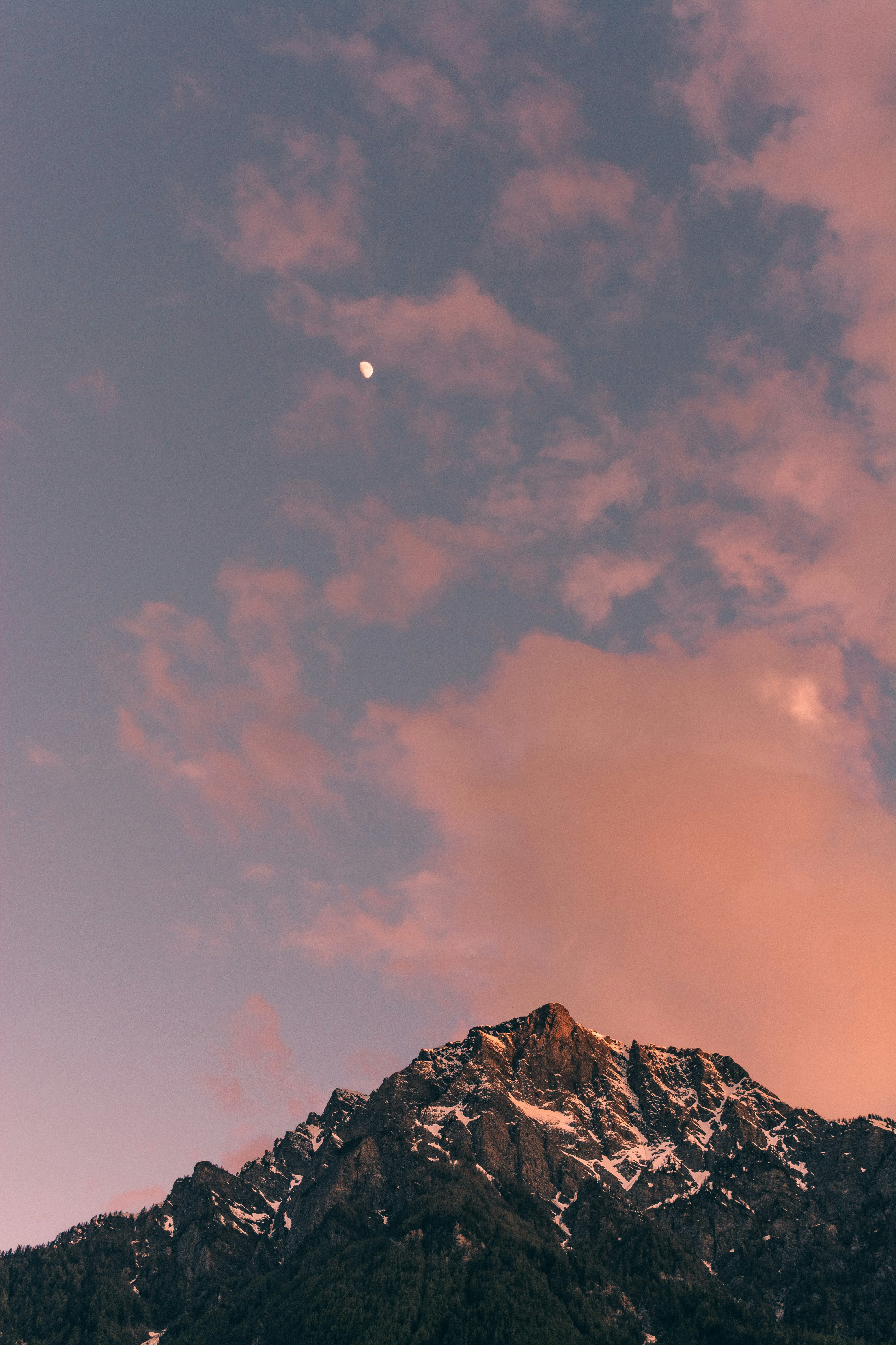 a very tall mountain with a moon in the sky