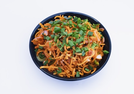 a black bowl filled with noodles and vegetables