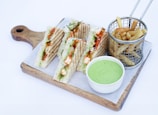 a tray with a cut in half sandwich next to a basket of fries
