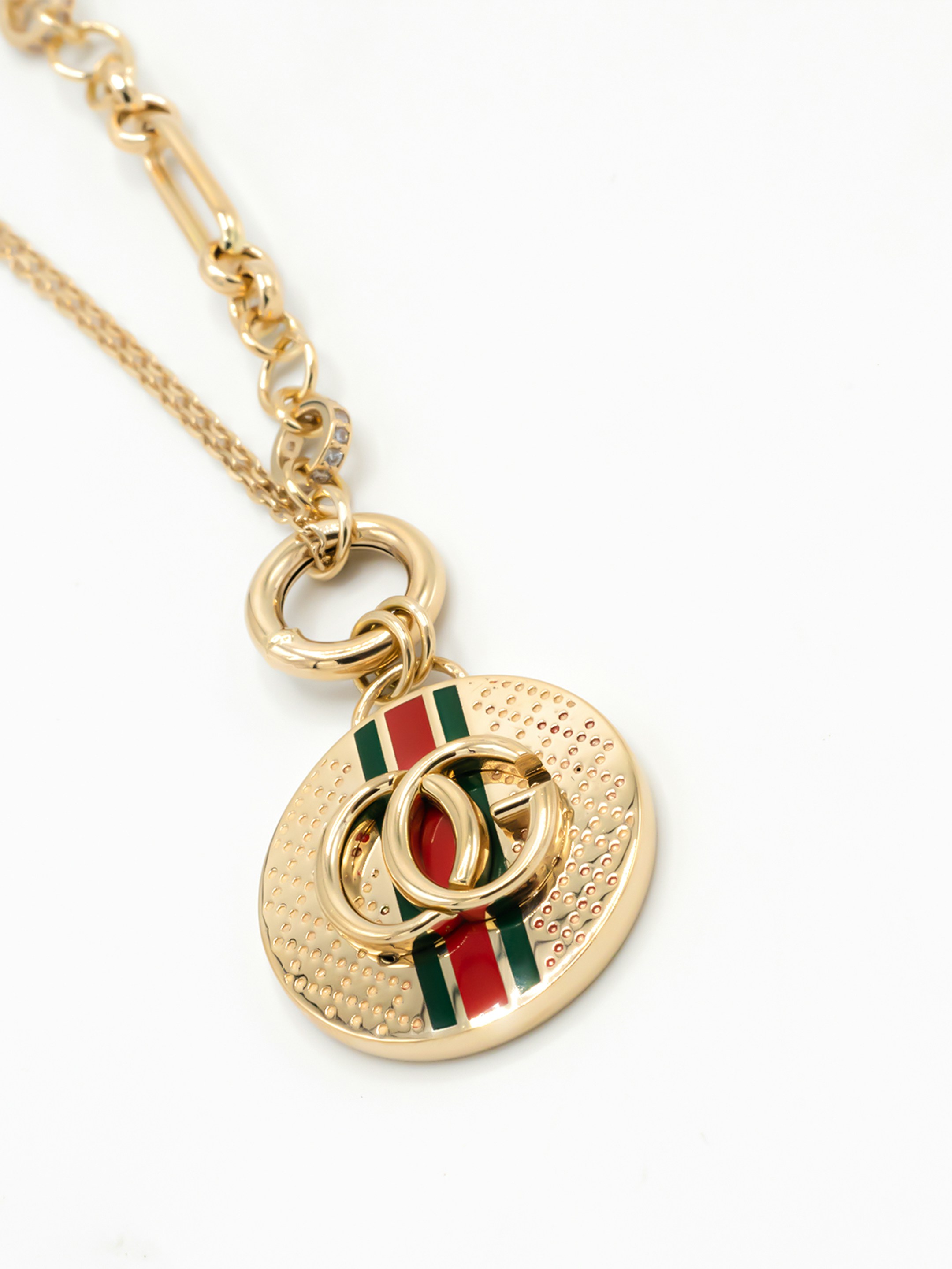 a gold necklace with a red, green and white trefoil charm