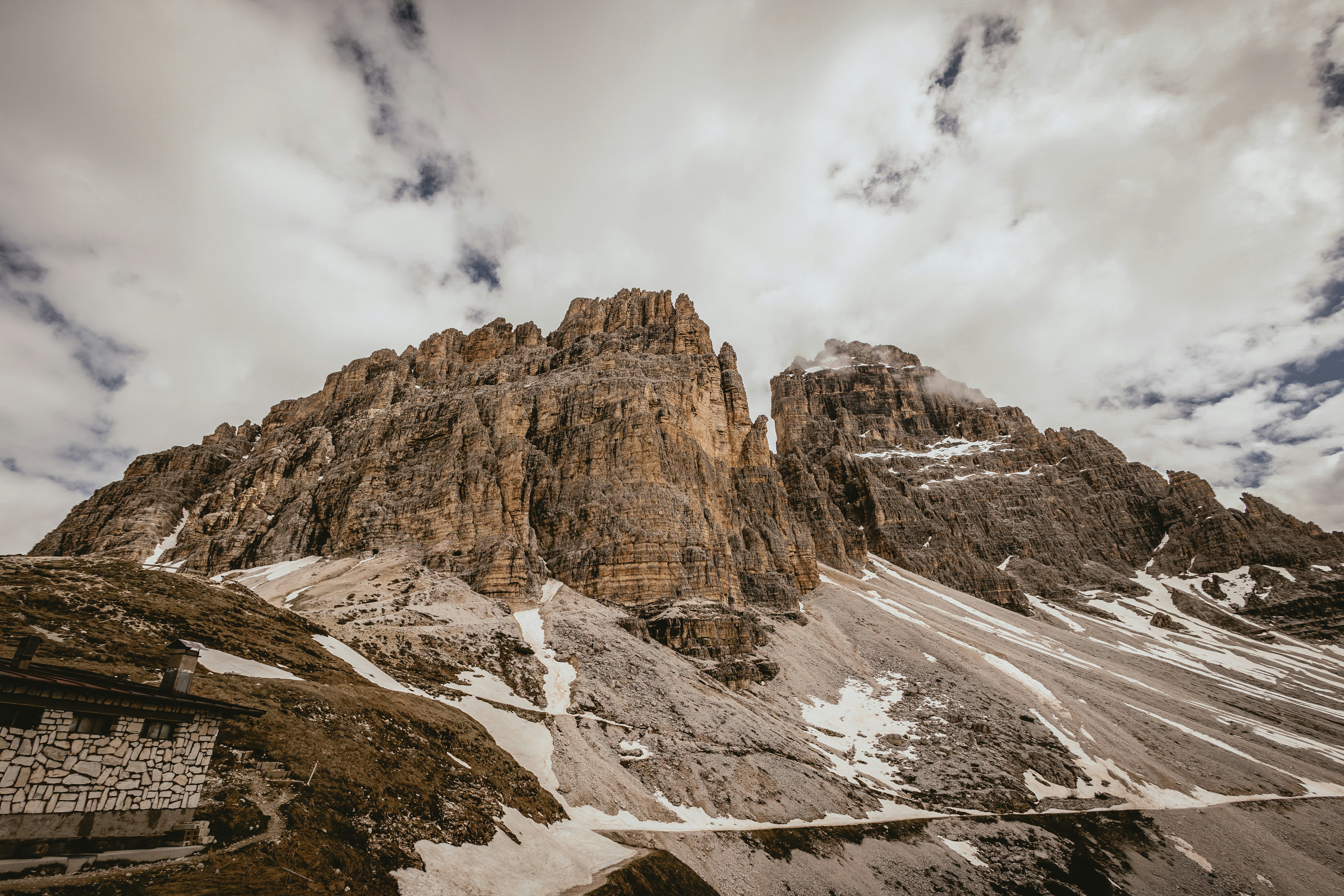 a mountain with snow on the ground and clouds in the sky