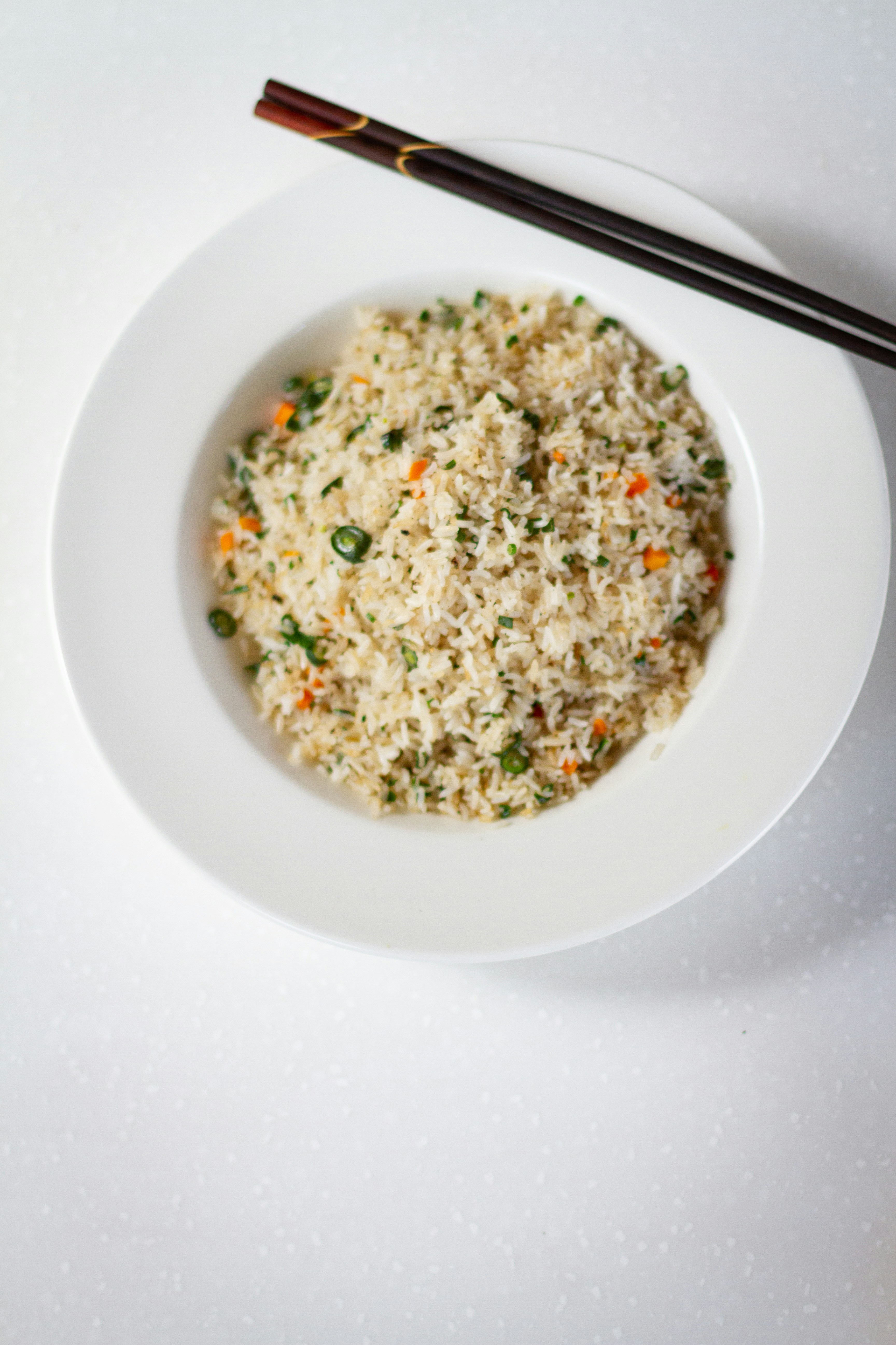 a bowl of rice and chopsticks on a white table