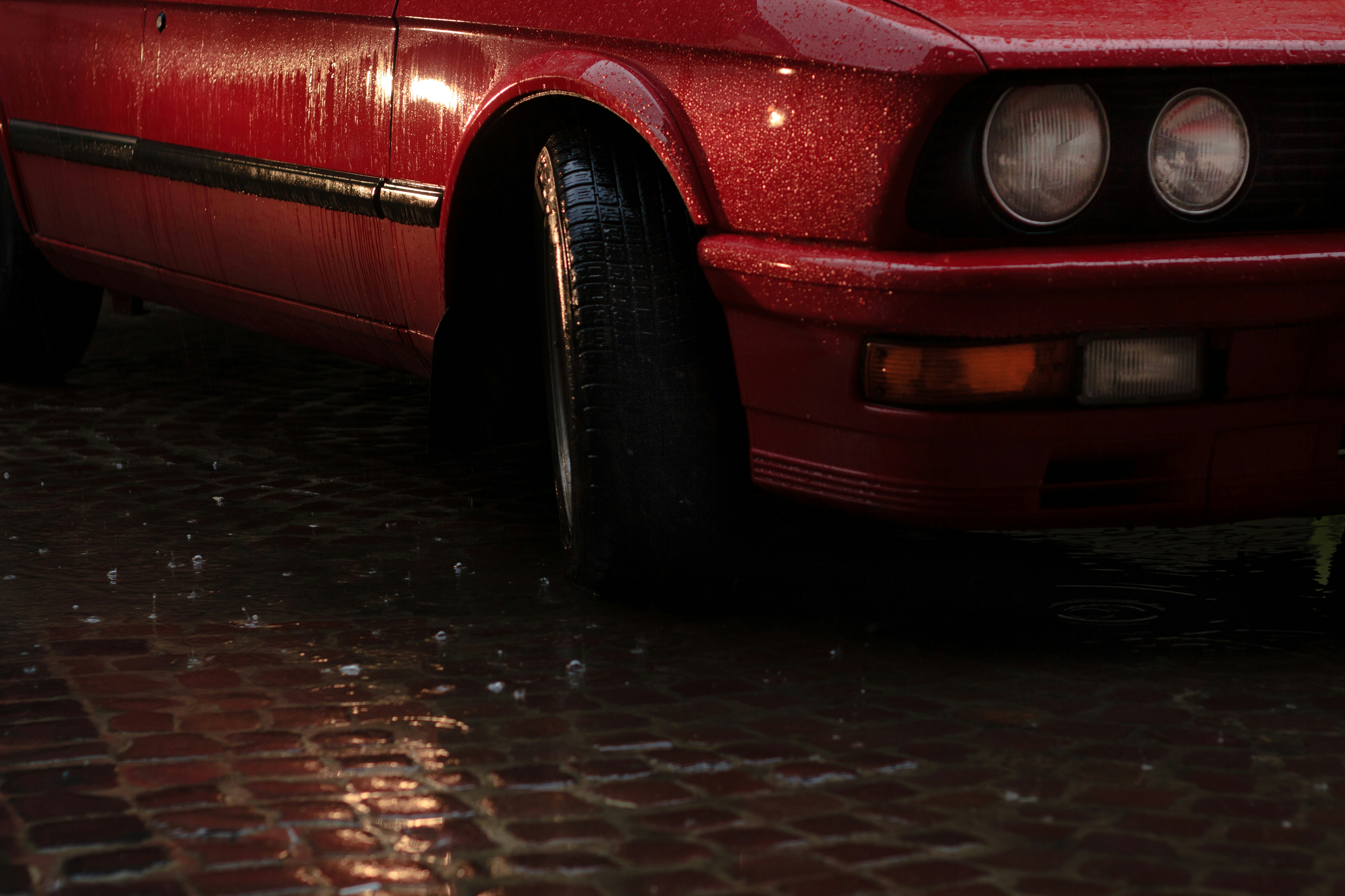 a red car is parked on a cobblestone street